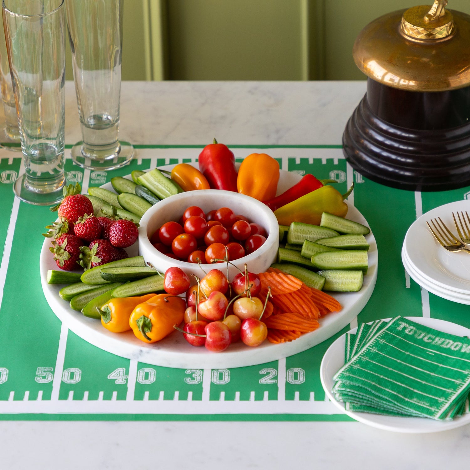 Marble Chip and Dip Server with fruits and veggies atop, Touchdown Cocktail Napkins, a gold trophy, and glasses, plates and forks on the Touchdown Runner.