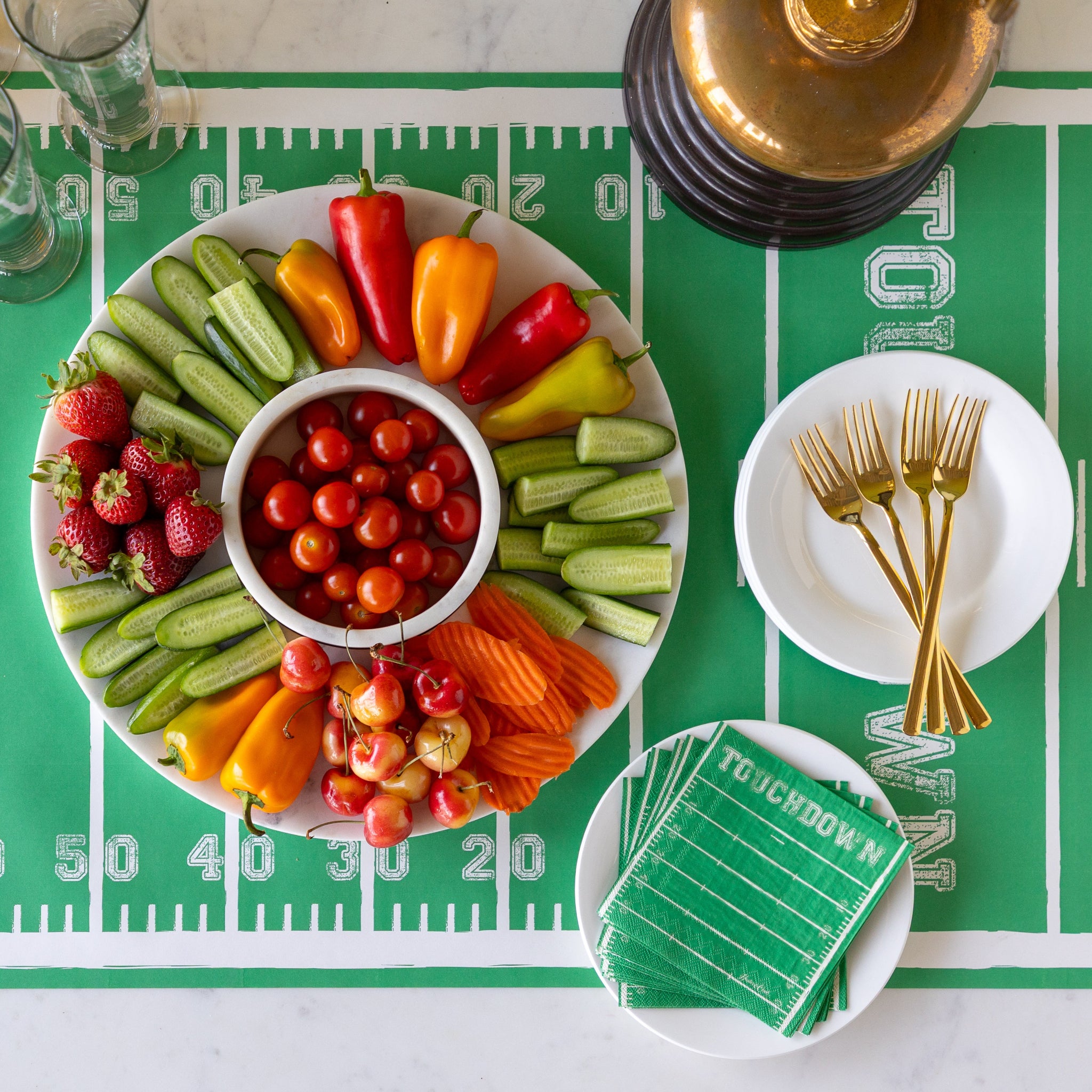 Marble Chip and Dip Server with fruits and veggies atop, Touchdown Cocktail Napkins, a gold trophy, and glasses, plates and forks on the Touchdown Runner.