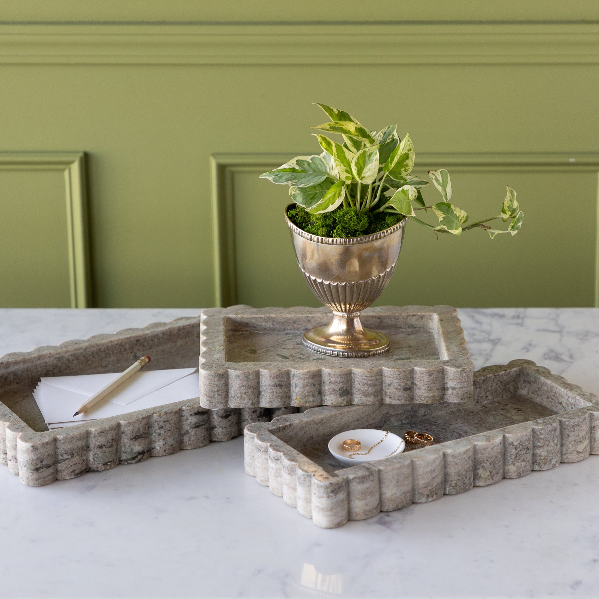Intricate Scallop Marble Trays in 3 sizes with a potted plant in the small, trinket dish with jewelry in the medium and envelopes and a pencil in the large.