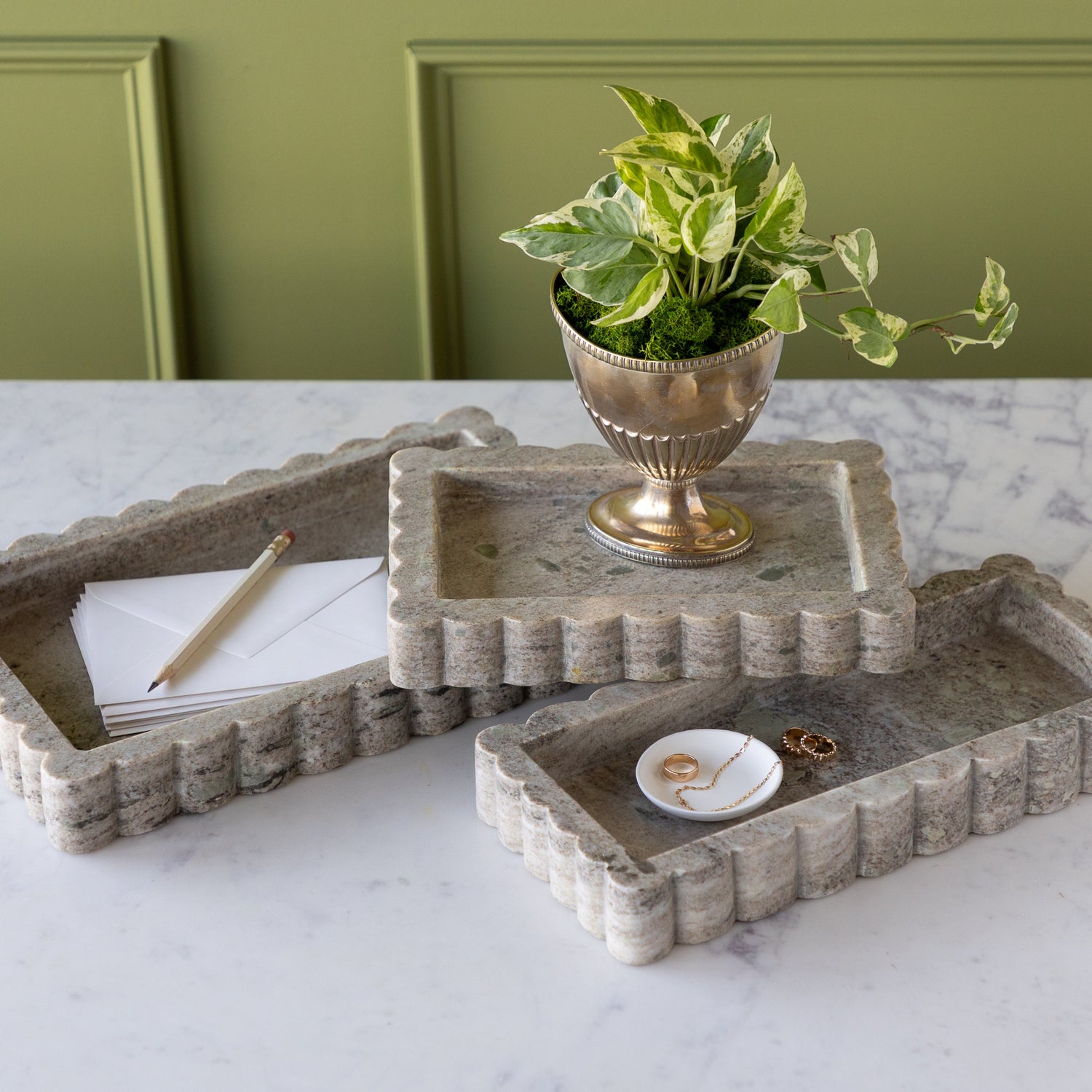 Intricate Scallop Marble Trays in 3 sizes with a potted plant in the small, trinket dish with jewelry in the medium and envelopes and a pencil in the large.