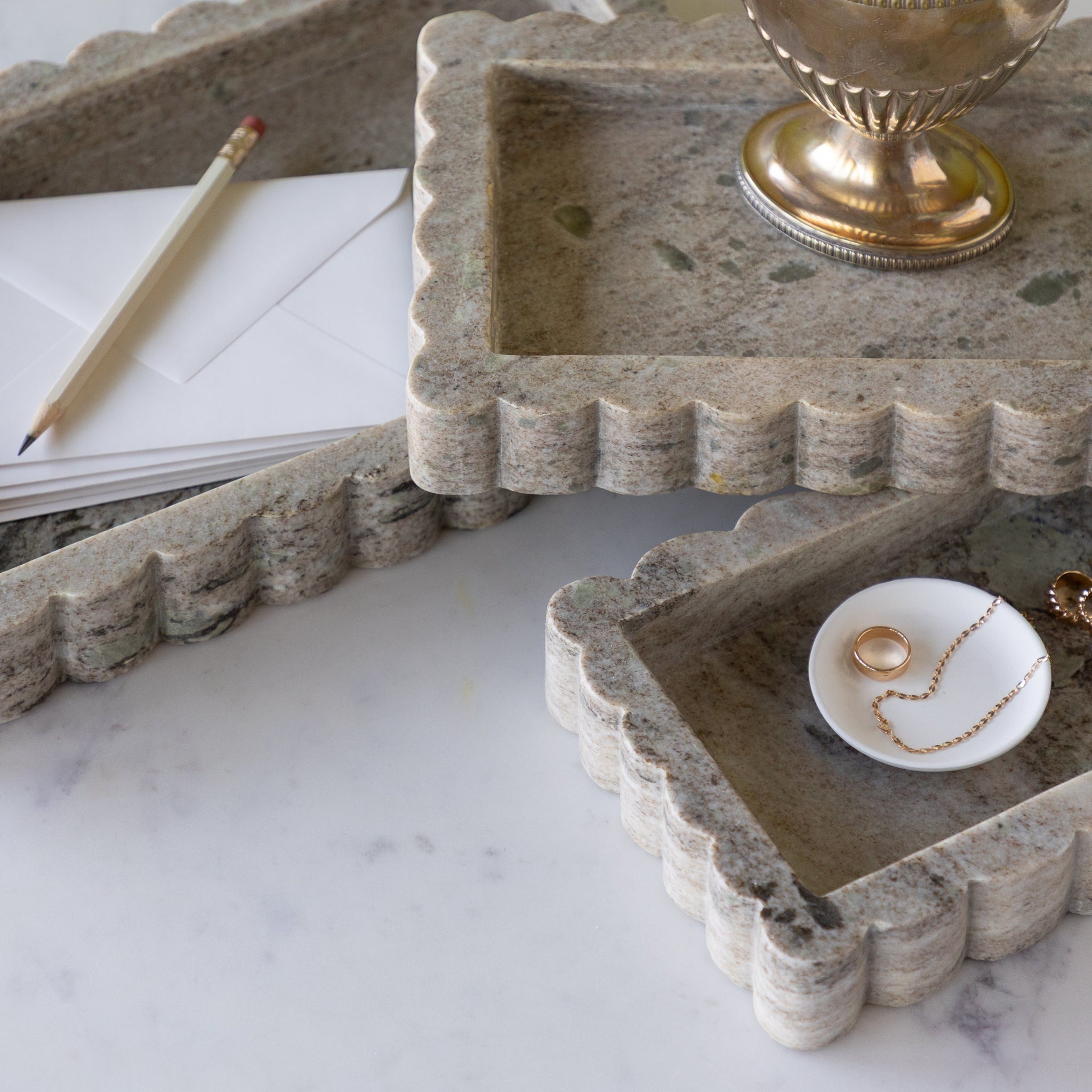 Intricate Scallop Marble Trays on a marble surface with stationery items.