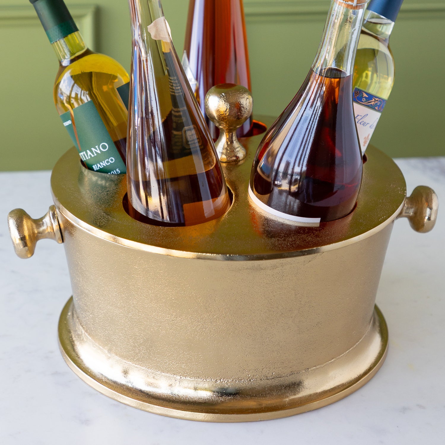 Gold Raw Aluminum Bottle Holder with 5 wine bottles, a knob in the center and on both sides of the bucket.