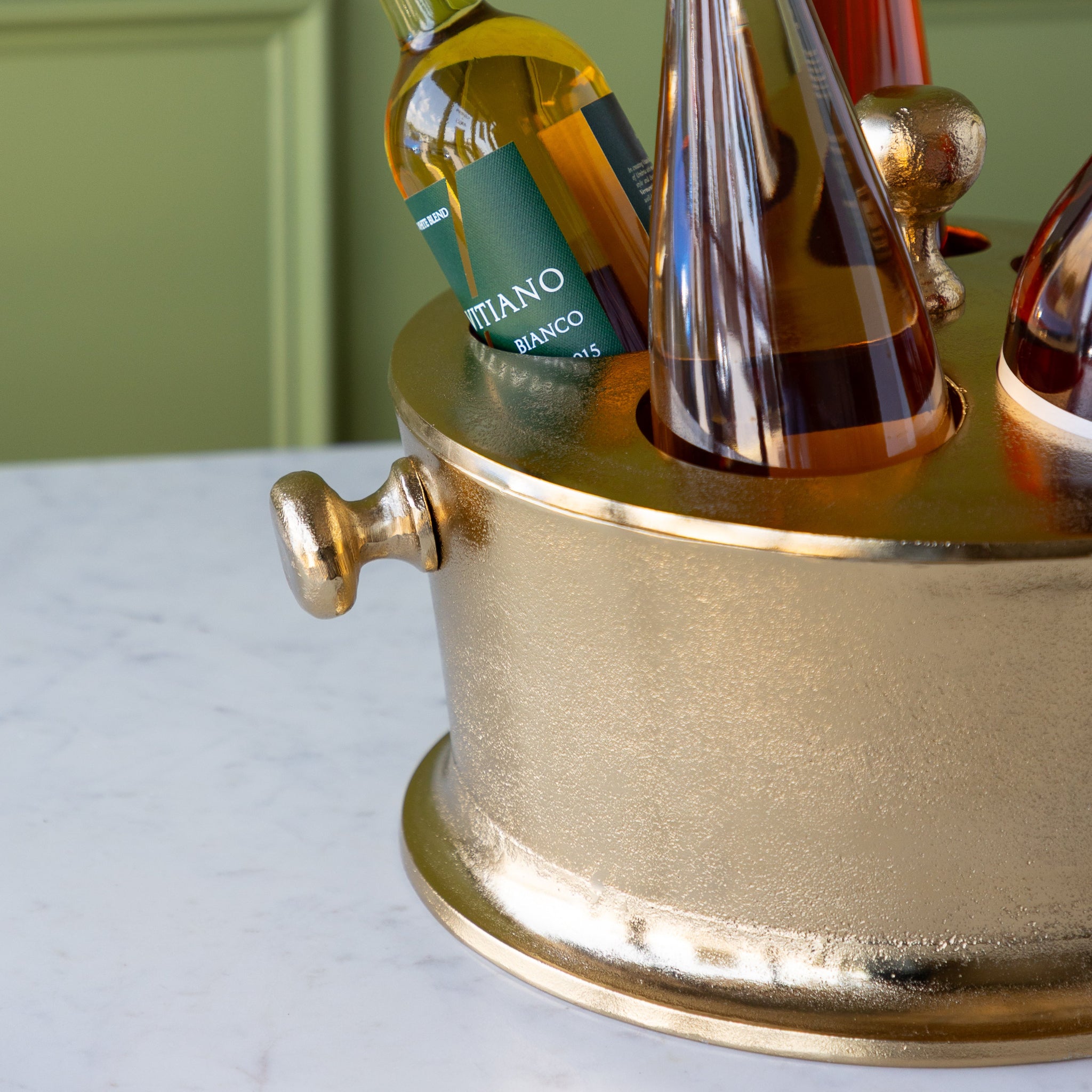Gold Raw Aluminum Bottle Holder with 5 wine bottles, a knob in the center and on the side of the bucket.