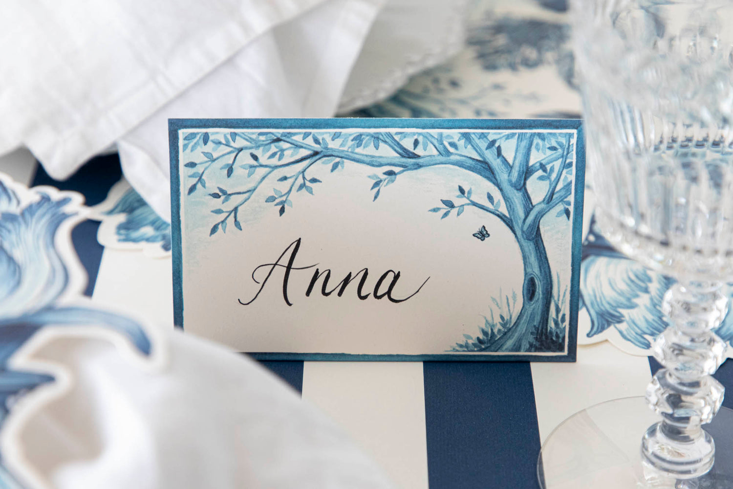 A Indigo Meadow place card by Hester &amp; Cook with a tree and butterfly on it, creating a tranquil atmosphere that makes guests feel extra special. Bonus feature: can also be used as buffet labels.