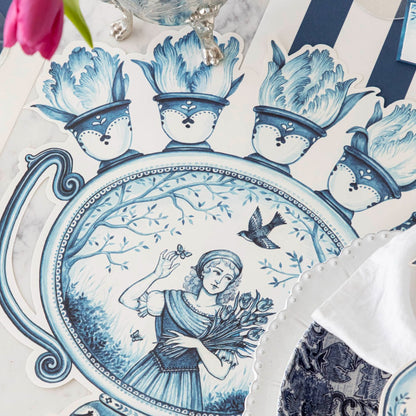 A Die-cut Indigo Meadow Placemat with a woman holding flowers, featuring French pastoral toile design by Hester &amp; Cook.