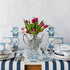 A blue and white table setting with a vase of tulips and Hester & Cook vintage silver-plated tea servers.