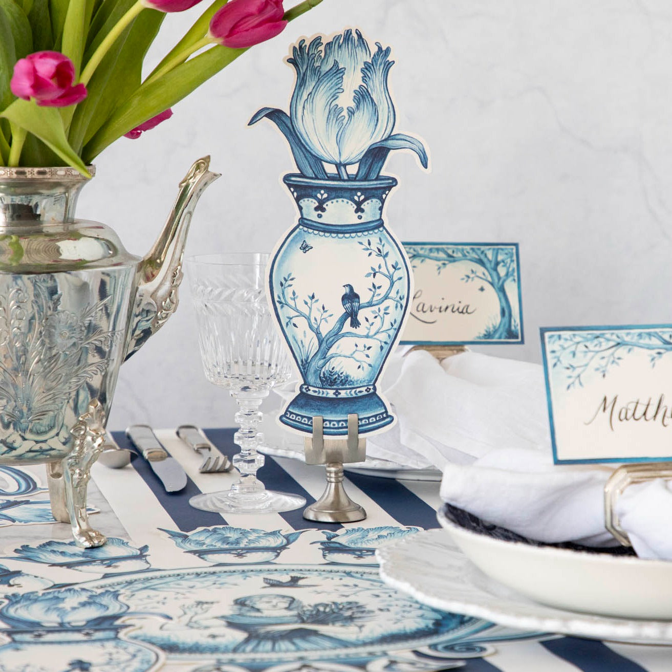 A versatile Indigo Tulip Table Accent featuring a blue and white table setting with a vase and tulips by Hester &amp; Cook.