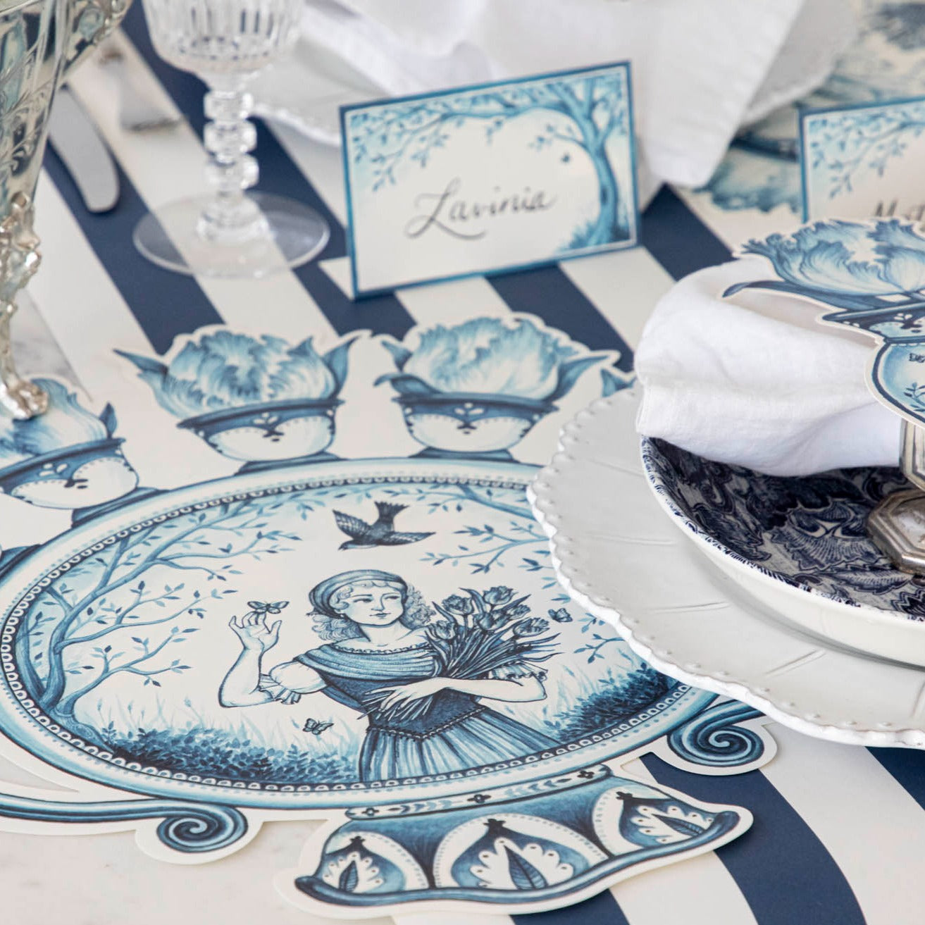A French pastoral toile table adorned with Die-cut Indigo Meadow Placemats featuring tulip vase designs by Hester &amp; Cook.