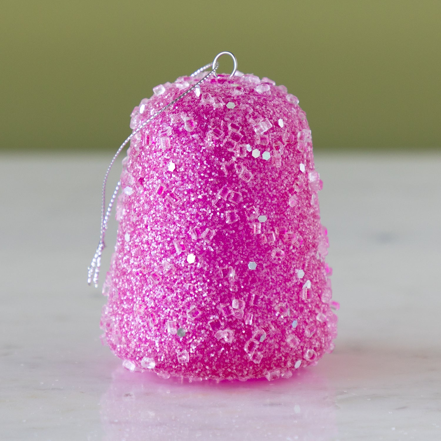 Pink glittery gum drop ornament on a neutral background.