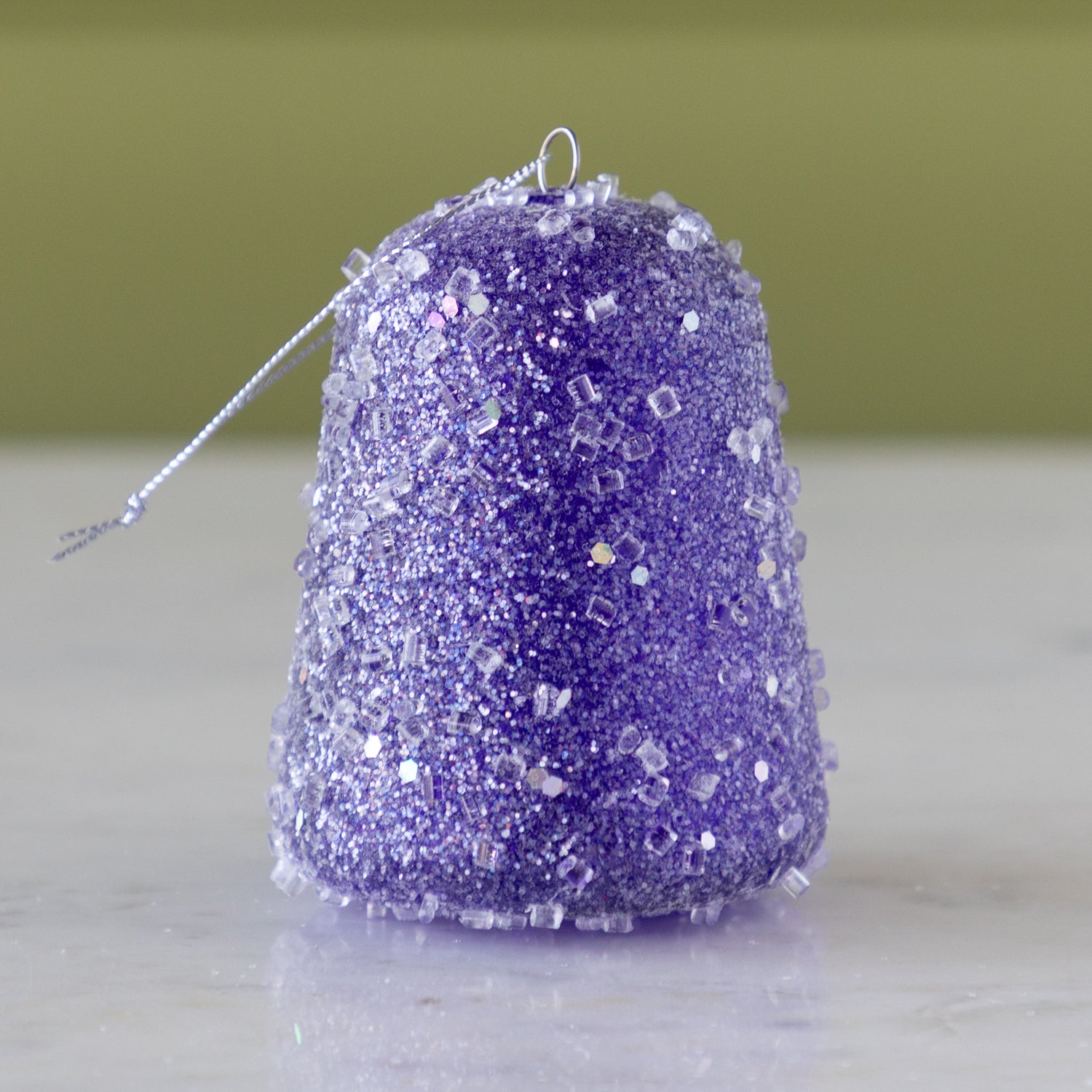 Purple glittery gum drop ornament on a neutral background.