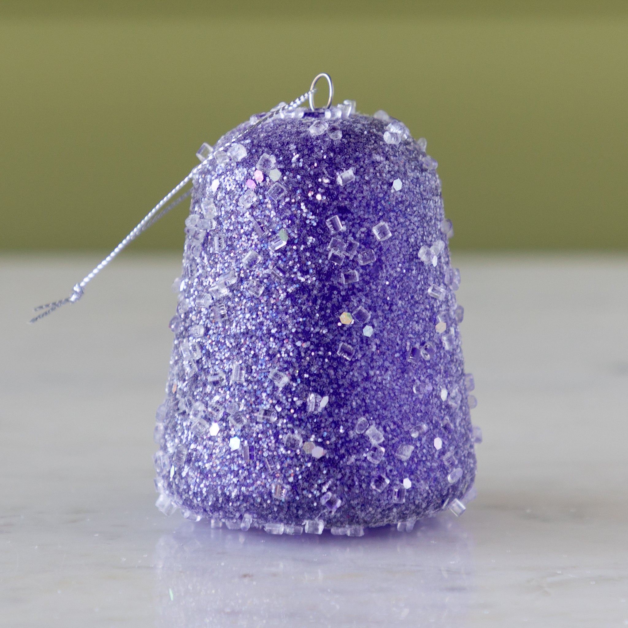 Purple glittery gum drop ornament on a neutral background.