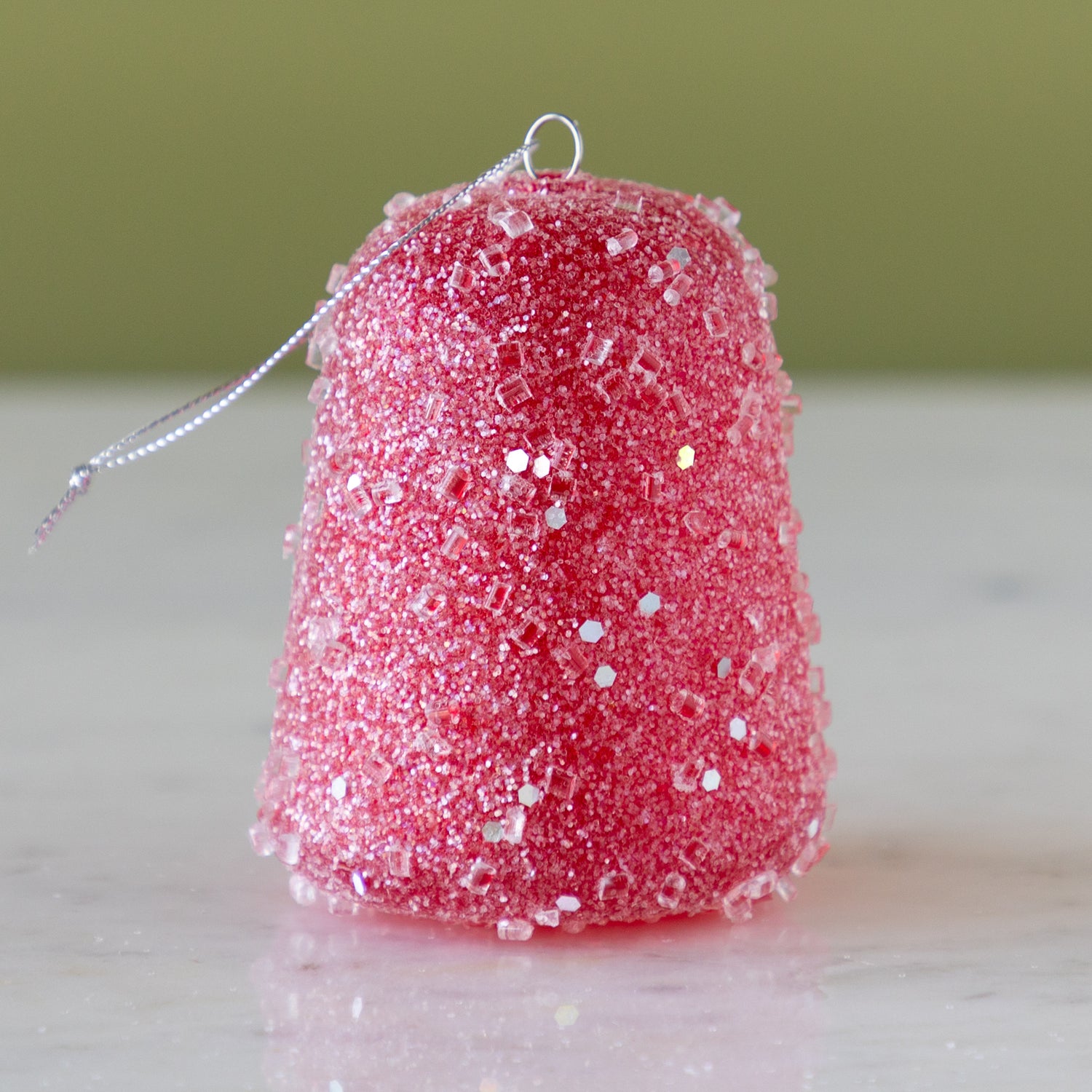 Red glittery gum drop ornament on a neutral background.