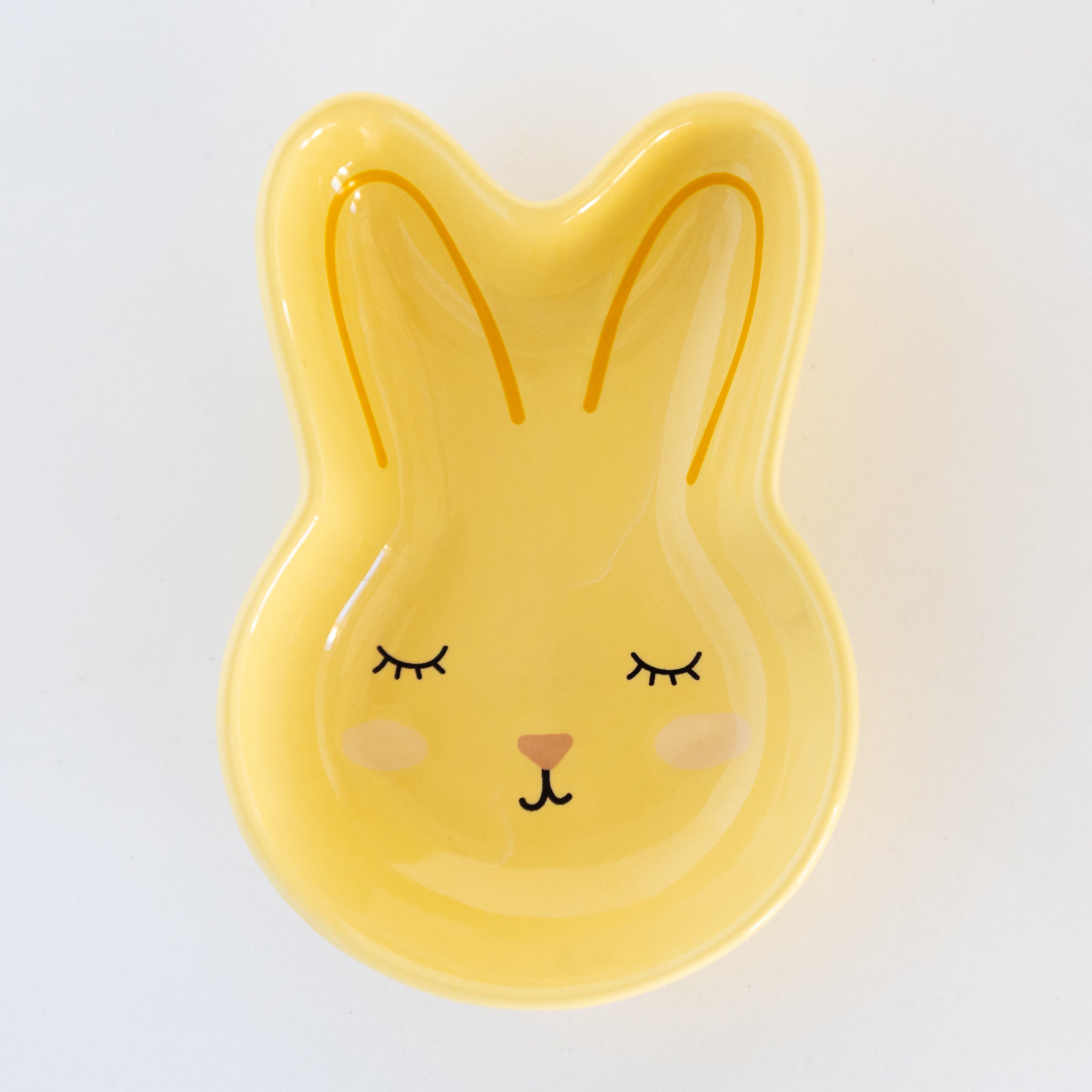 Yellow rabbit-shaped dish with a cute face on a white background.