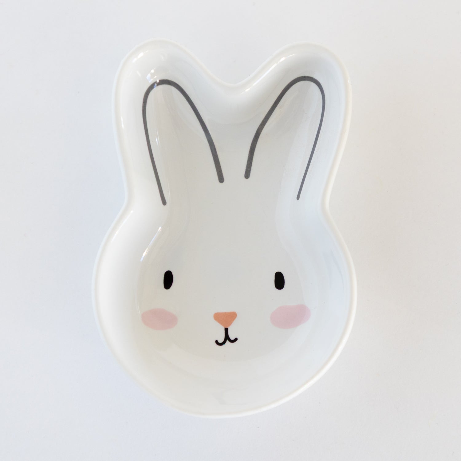 White, ceramic rabbit-shaped dish with a cute face on a white background.