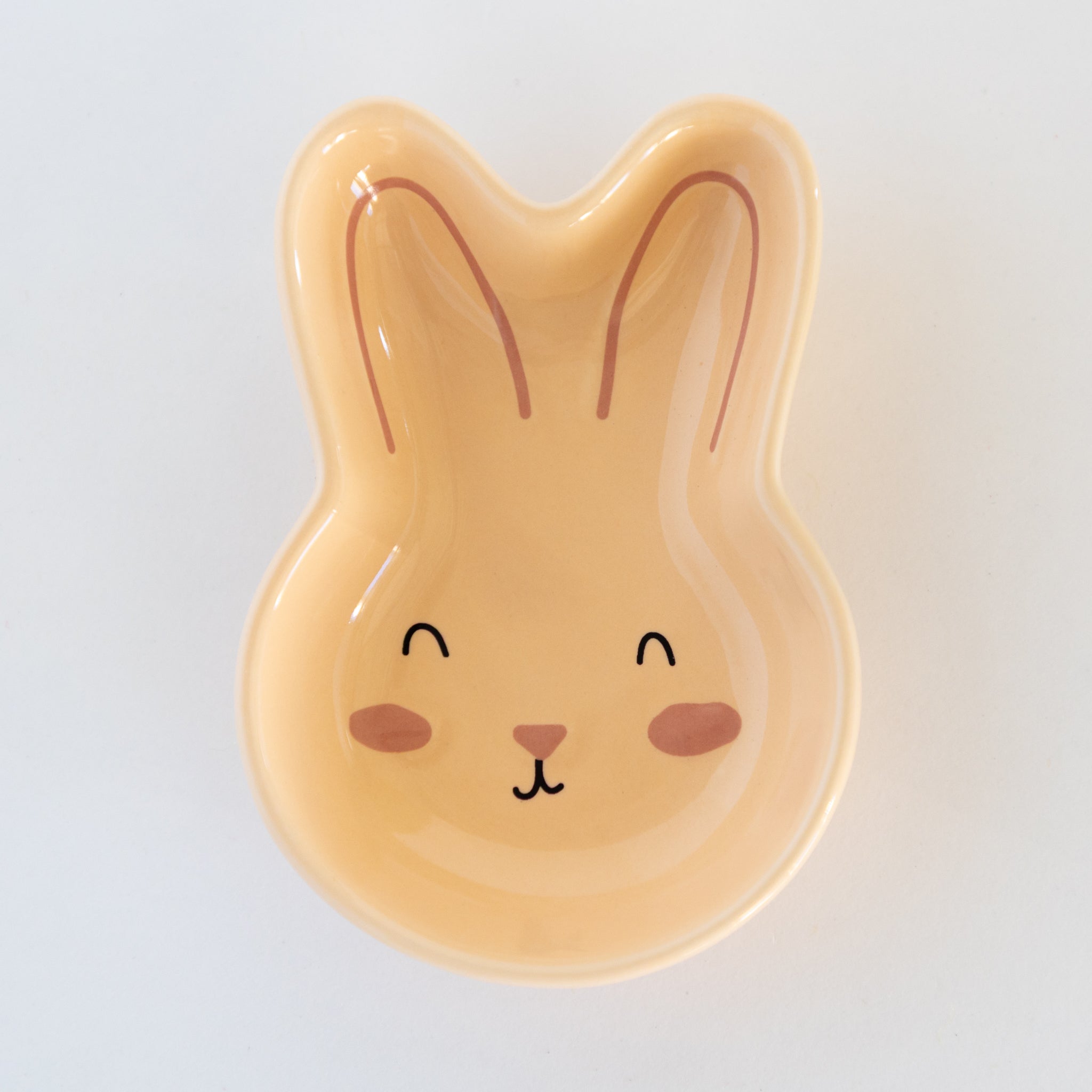 Peach, ceramic rabbit-shaped bowl on a marble table.