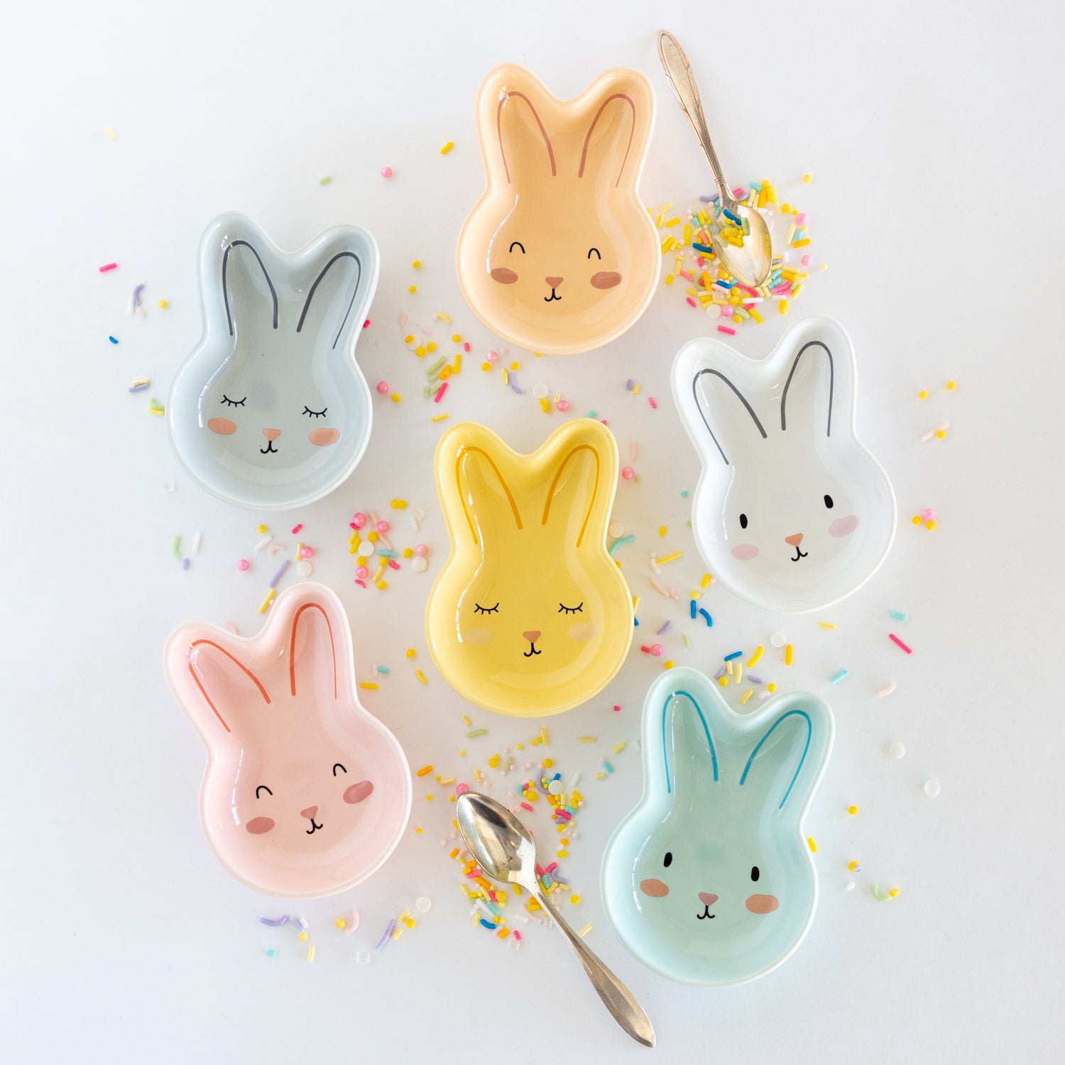 Set of six bunny-shaped ceramic bowls on a marble table with colorful sprinkles.