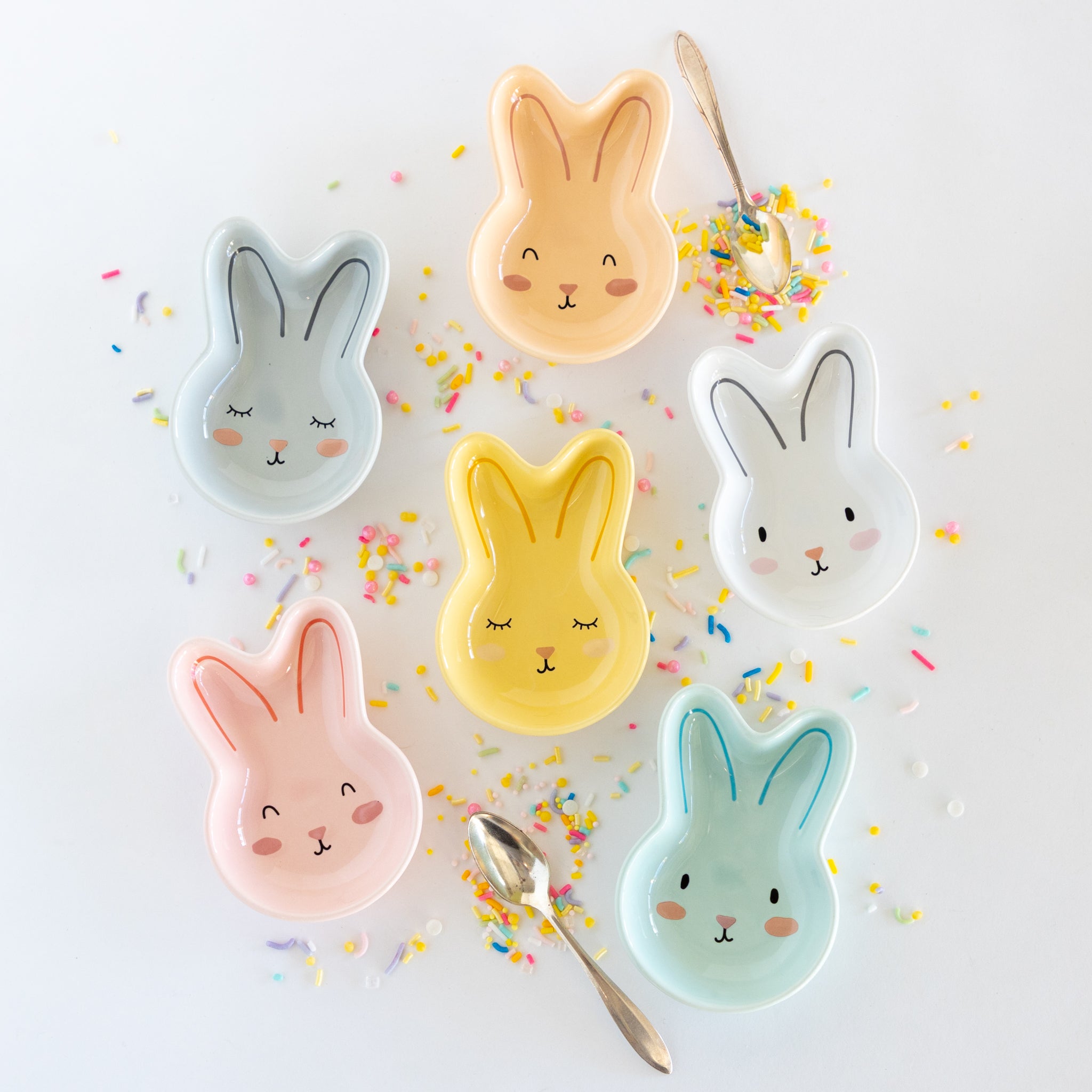 Set of six bunny-shaped ceramic bowls on a marble table with colorful sprinkles.