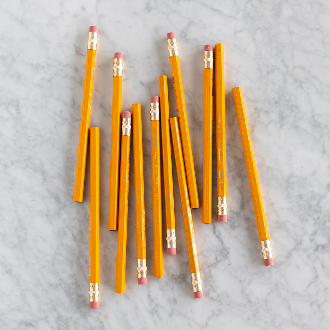 Yellow Jumbo Hex pencils scattered on a marble surface. 