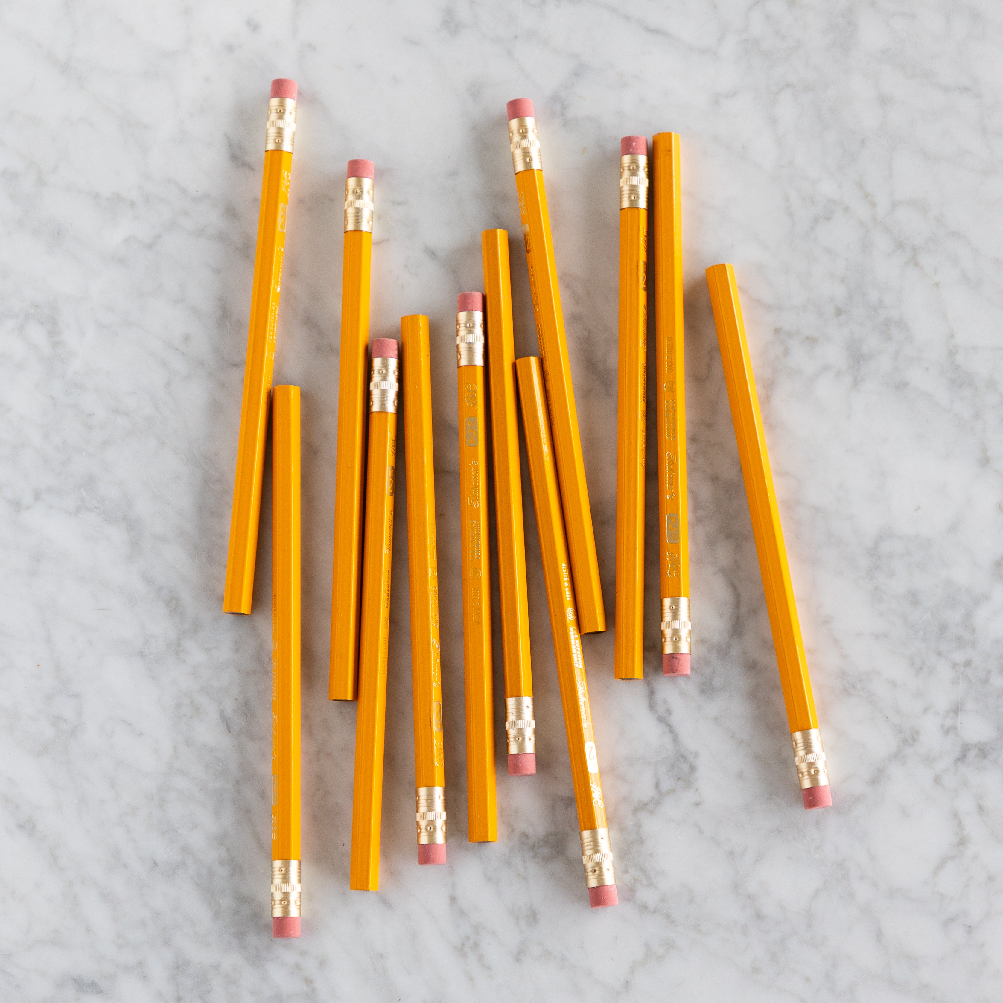 Yellow Jumbo Hex pencils scattered on a marble surface. 