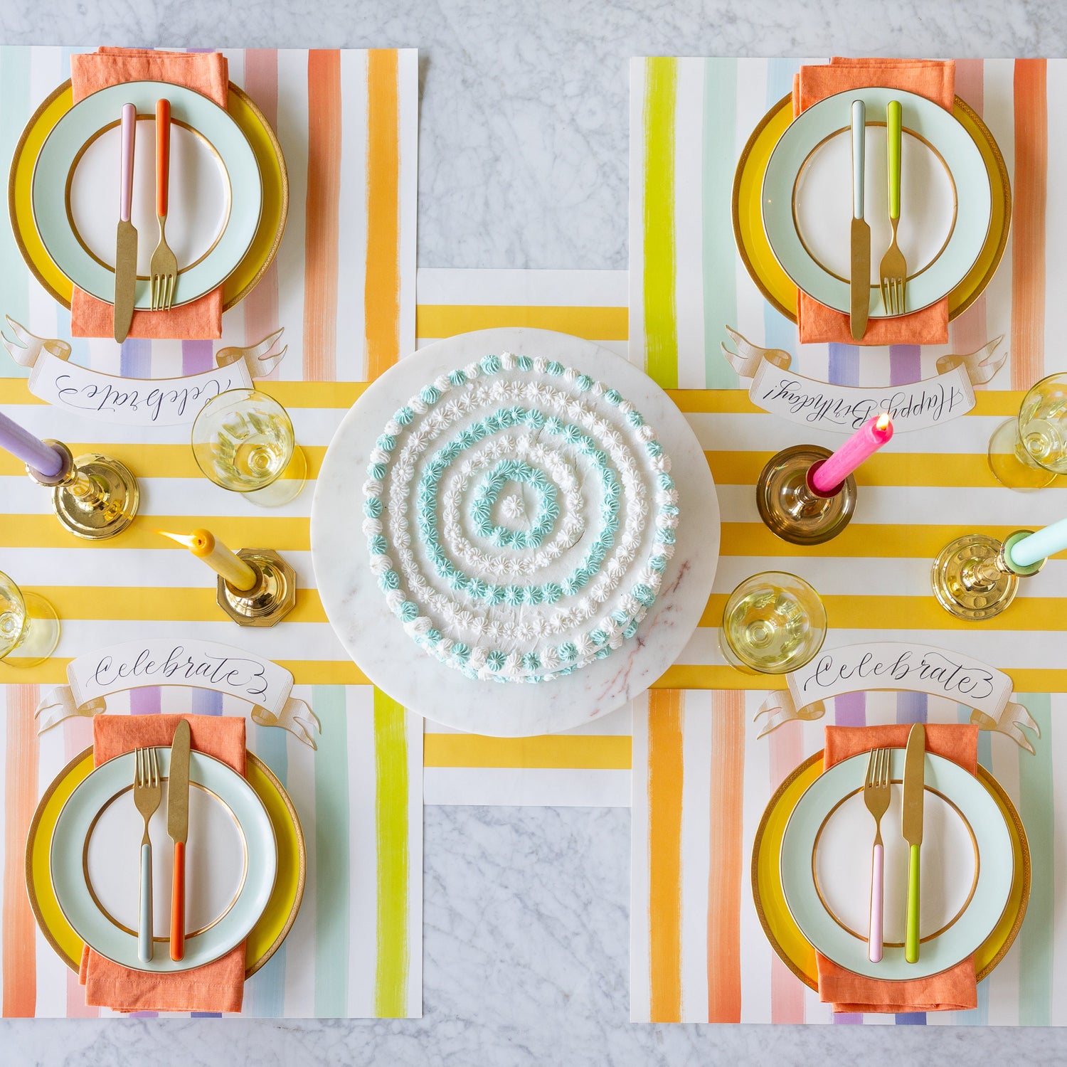 Colorful table setting with the Sorbet Painted Stripe Placemats, colorful plates and cutlery atop, and Classic Gold Banner Table Accents on the Marigold Classic Stripe Runner.