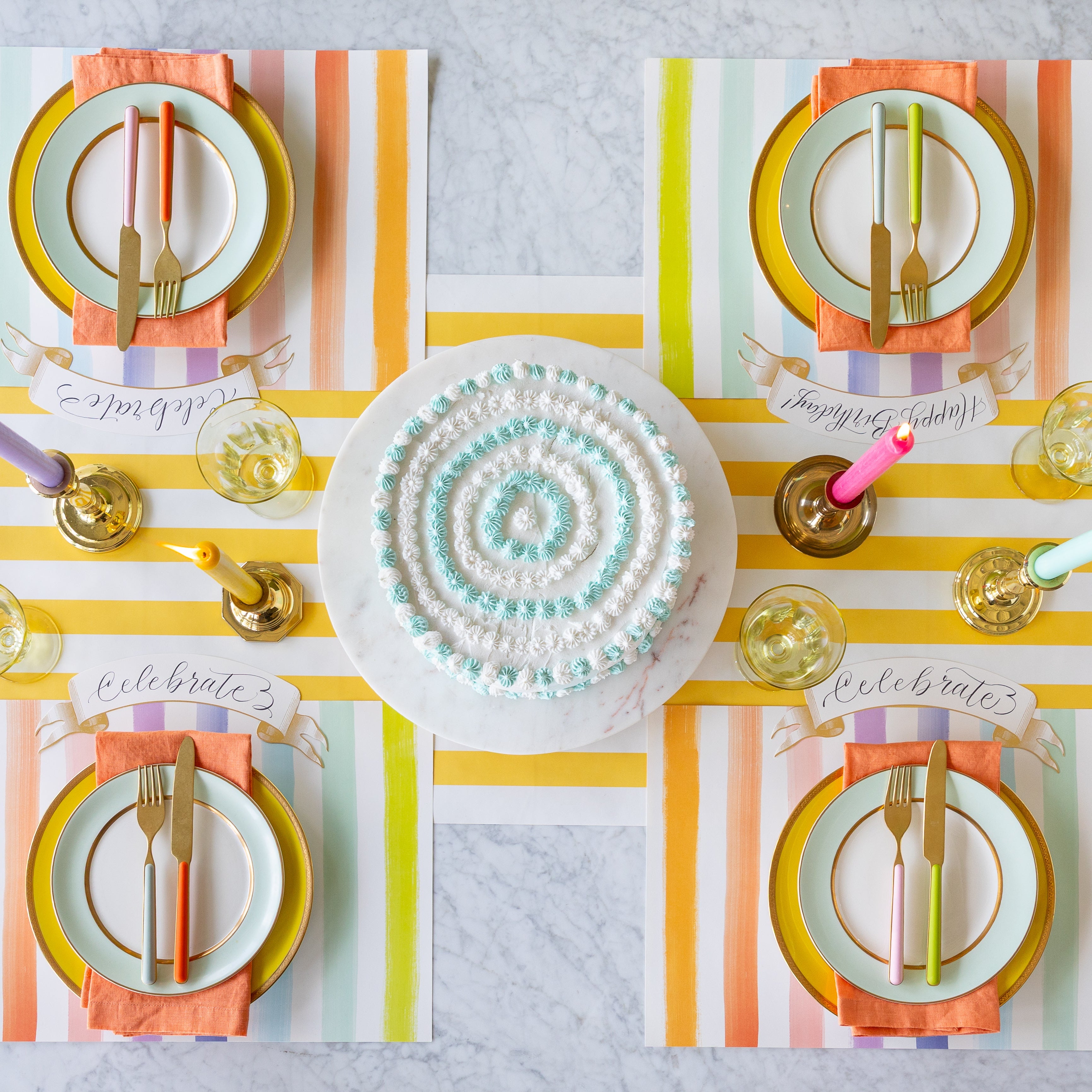 Colorful table setting with the Sorbet Painted Stripe Placemats, colorful plates and cutlery atop, and Classic Gold Banner Table Accents on the Marigold Classic Stripe Runner.