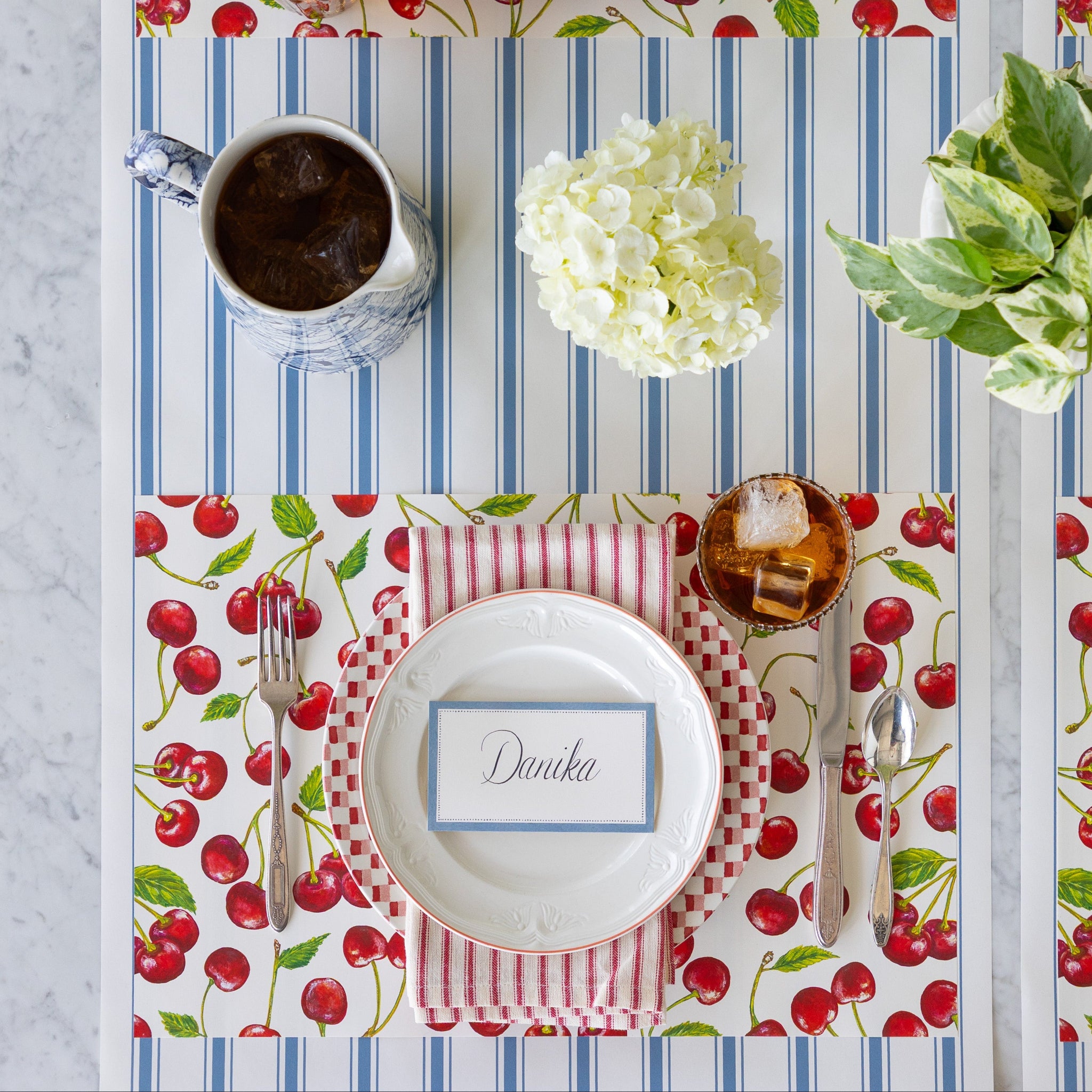 Table setting with the Cherries Placemat, Cornflower Blue Place Card, vintage dinnerware, and floral decorations on the Cornflower Blue Linen Stripe Runner.