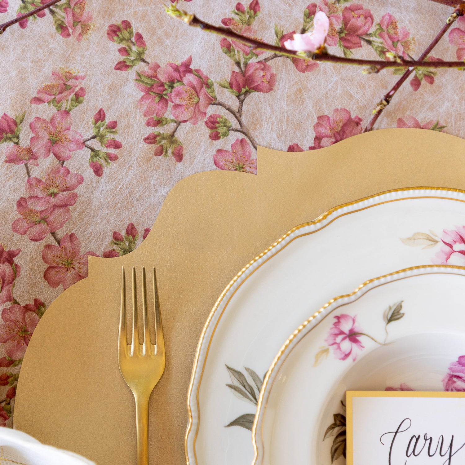 An elegant place setting featuring the Die-cut Gold French Frame Placemat on top of the Cherry Blossom Runner.