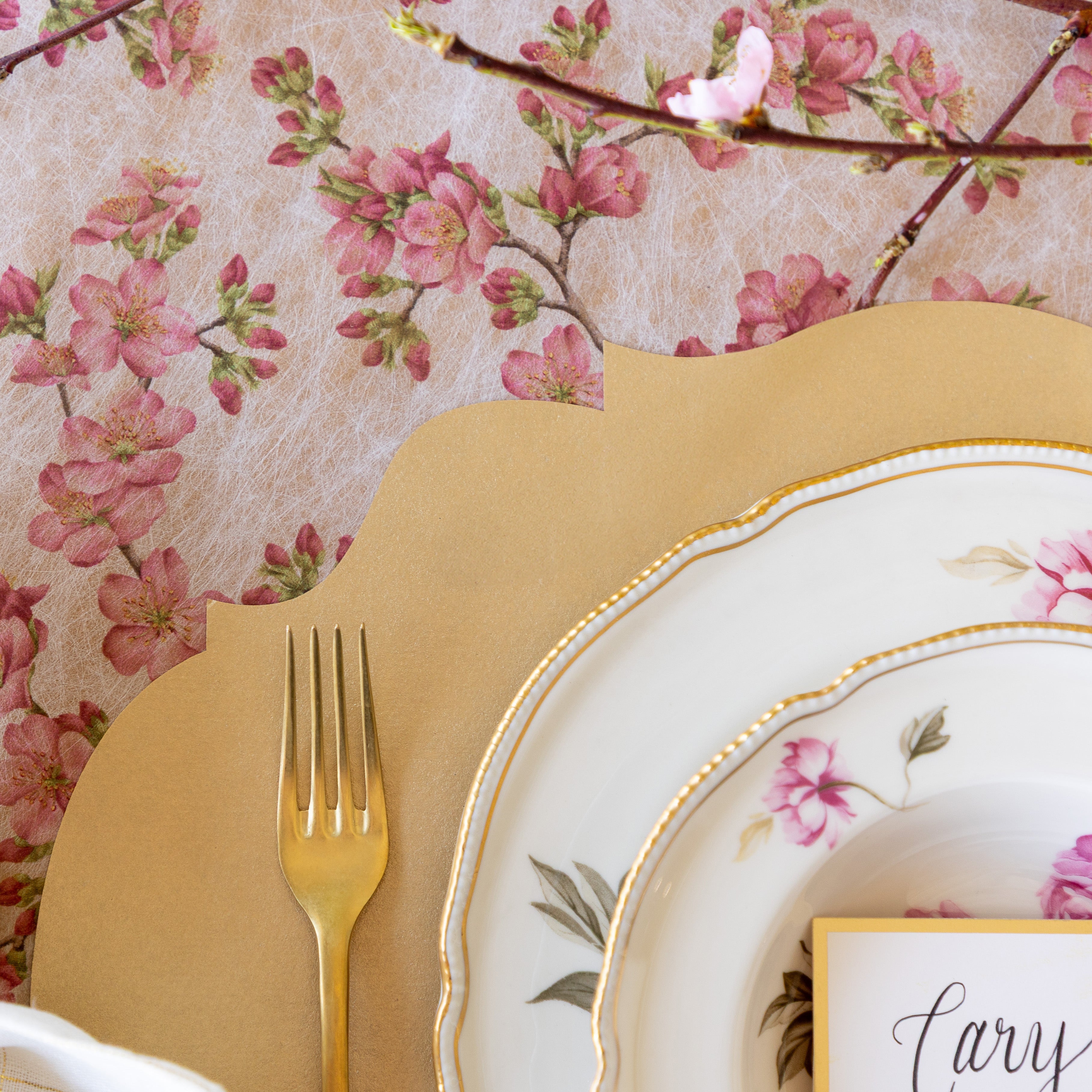 An elegant place setting featuring the Die-cut Gold French Frame Placemat on top of the Cherry Blossom Runner.