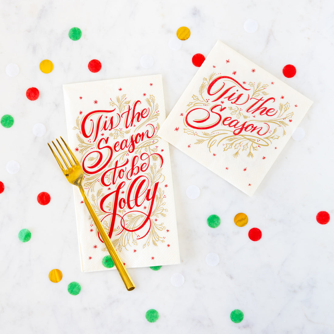 Tis the Season Cocktail and Guest Napkins arranged on a marble table with confetti and a gold fork.