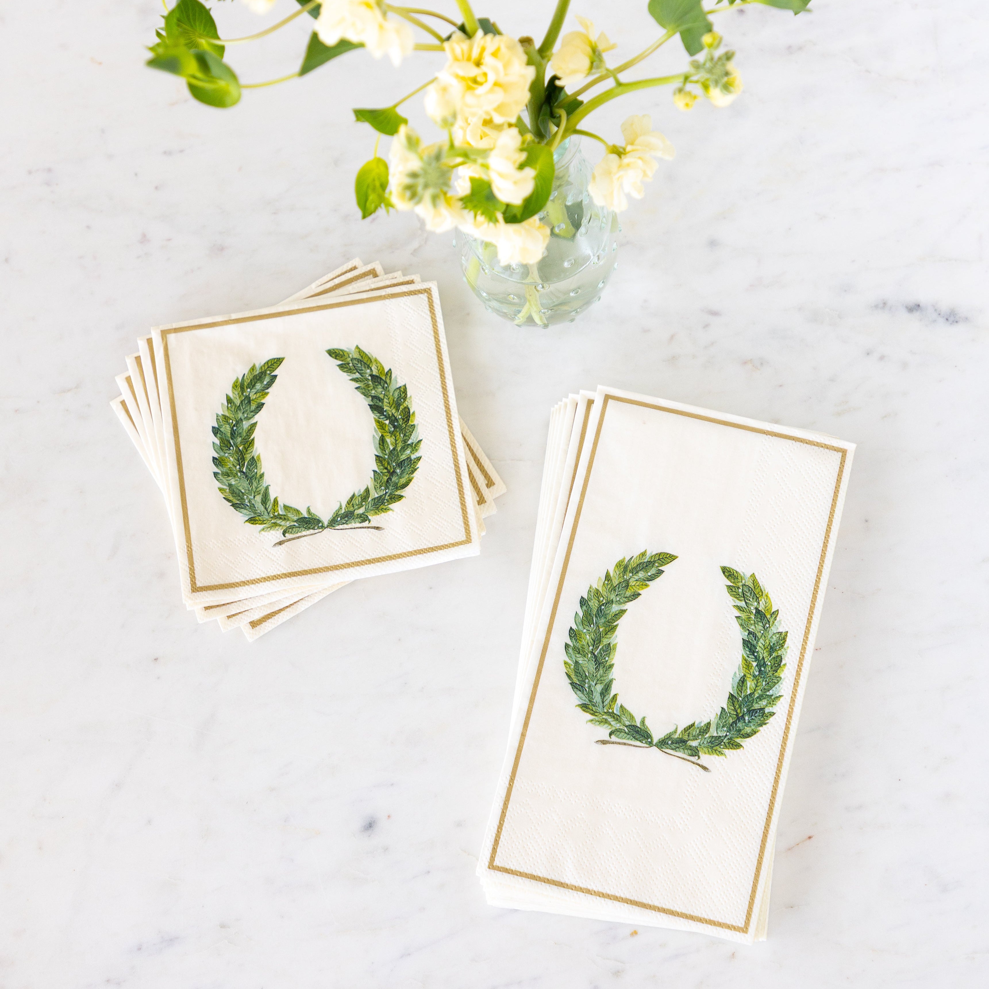 Laurel Wreath Cocktail and Guest Napkins next to a vase of flowers.