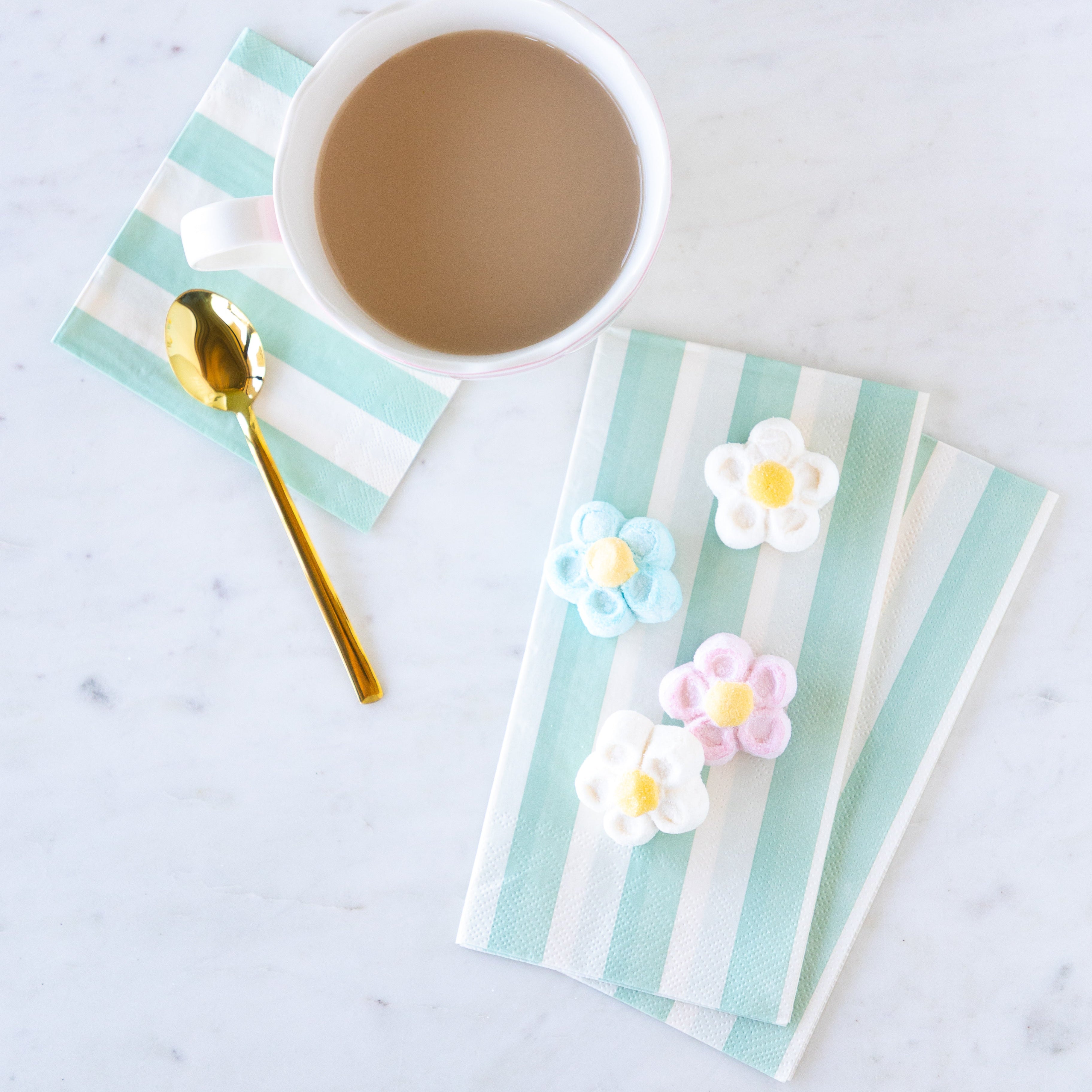 Cup of coffee with Seafoam Classic Stripe Guest and Cocktail Napkins and decorative flowers on a marble surface.
