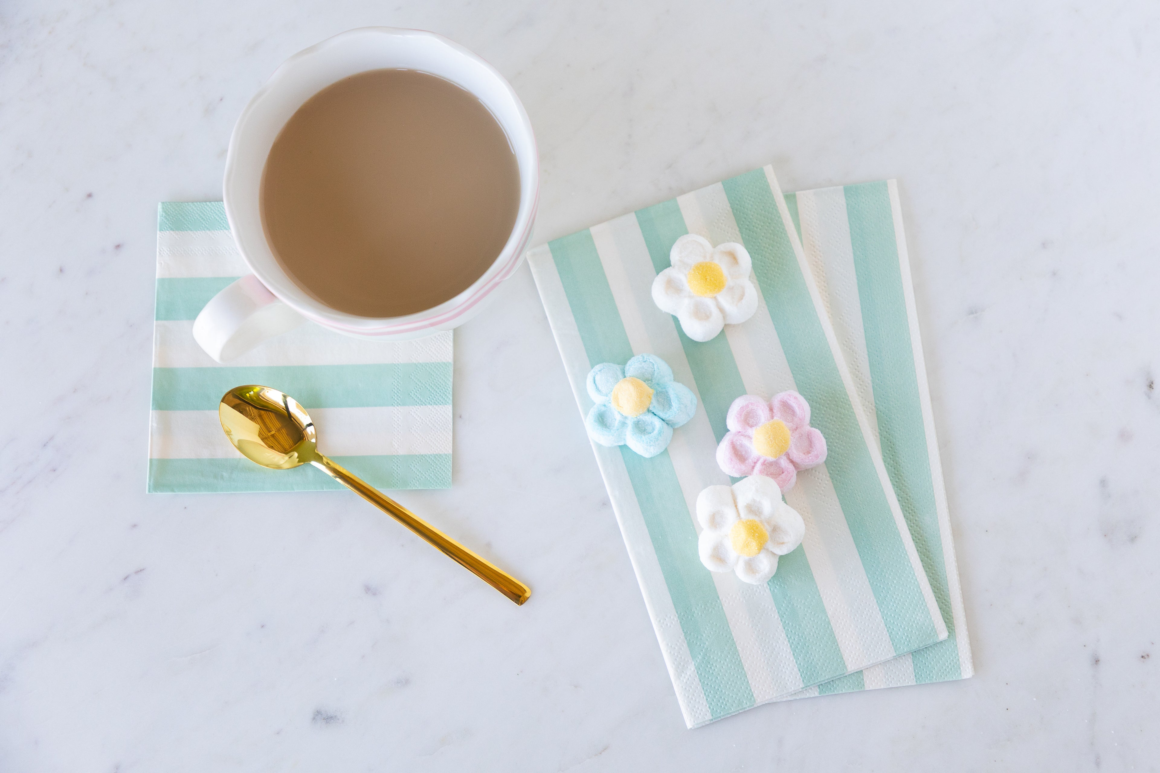 Cup of coffee with Seafoam Classic Stripe Guest and Cocktail Napkins and decorative flowers on a marble surface.