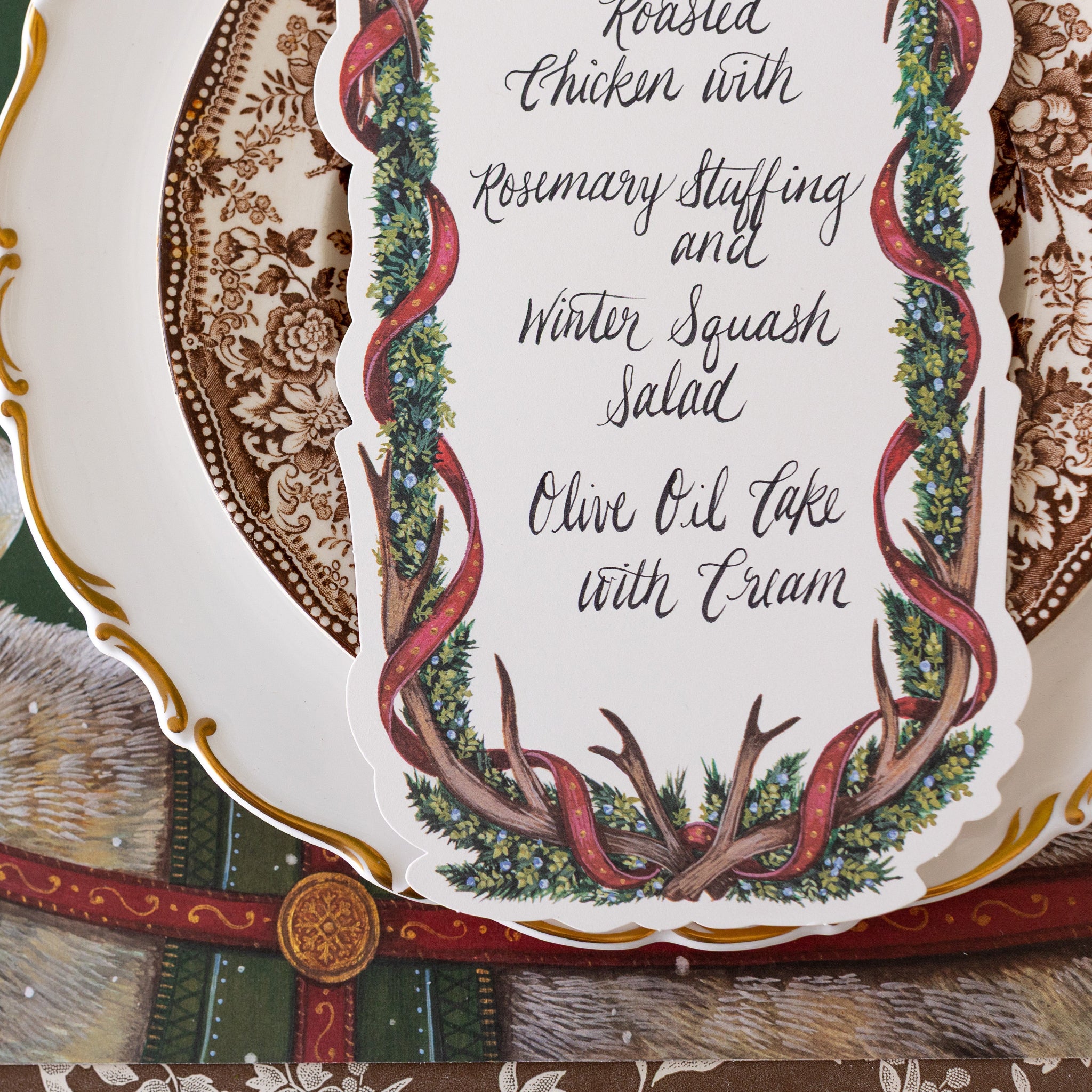 A close up of the Antler Garland Table Card with a Christmas menu written on it, on a place setting.