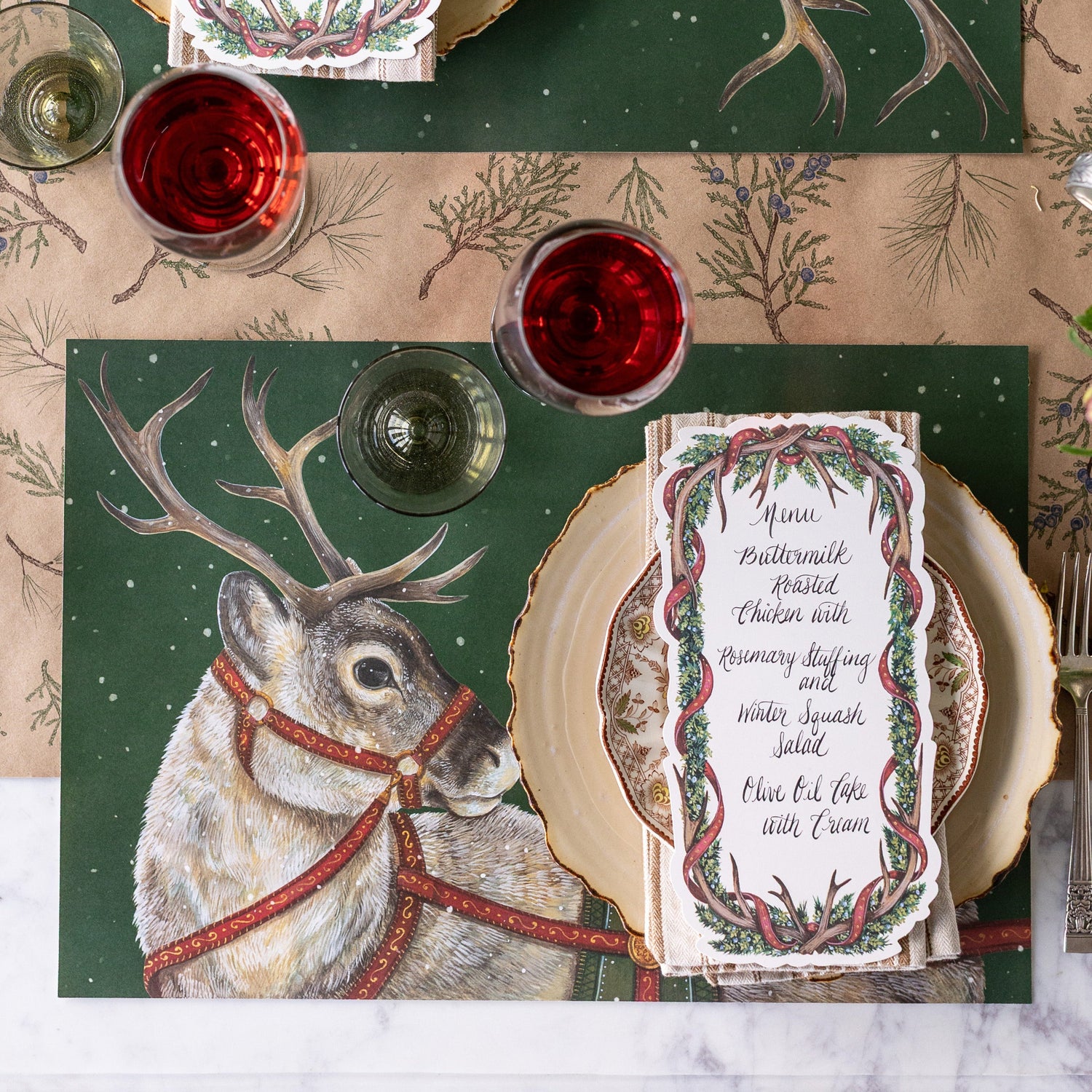 Decorative table setting with Holiday Reindeer Placemats and Antler Garland Table Cards on the Juniper Sprigs Runner.