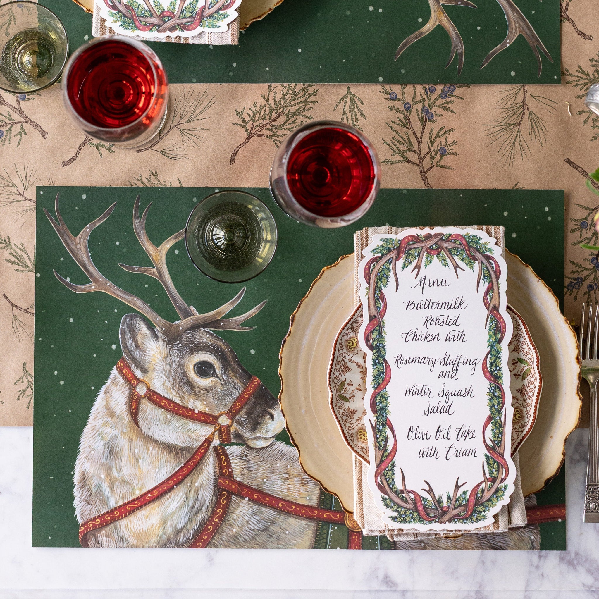 Decorative table setting with Holiday Reindeer Placemats and Antler Garland Table Cards on the Juniper Sprigs Runner.