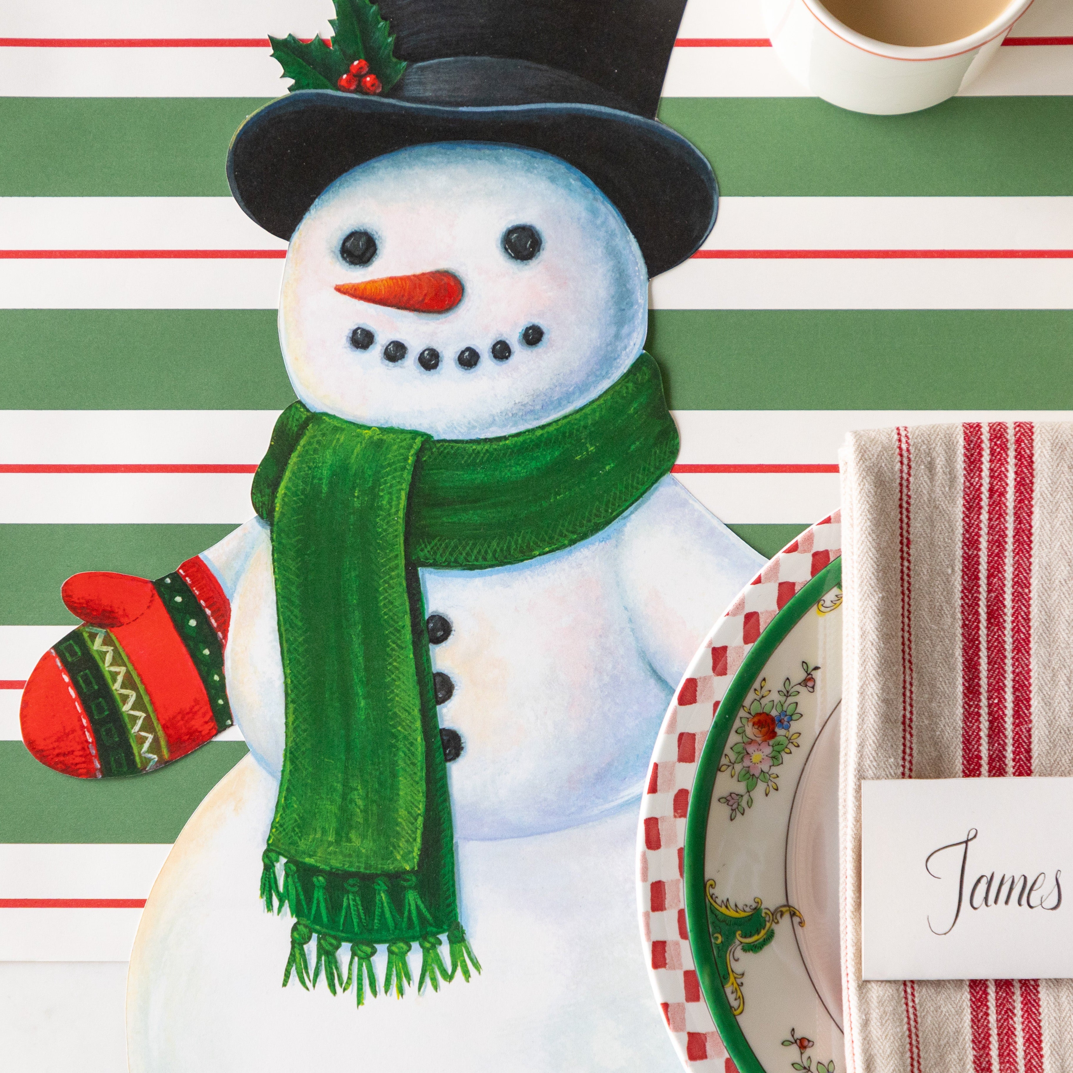 A festive place setting with the Die-cut Jolly Snowman Placemat on the Green &amp; Red Awning Stripe Runner.
