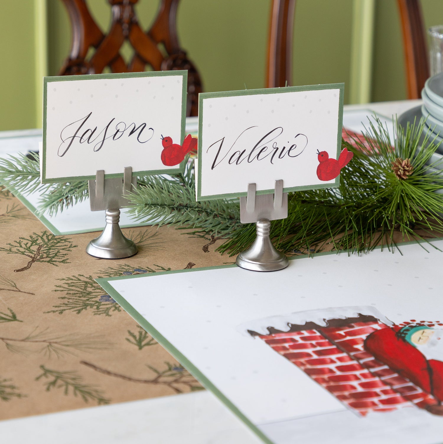 Table setting with Red Bird Place Cards held by Chrome Place Card Holders, behind a place setting.