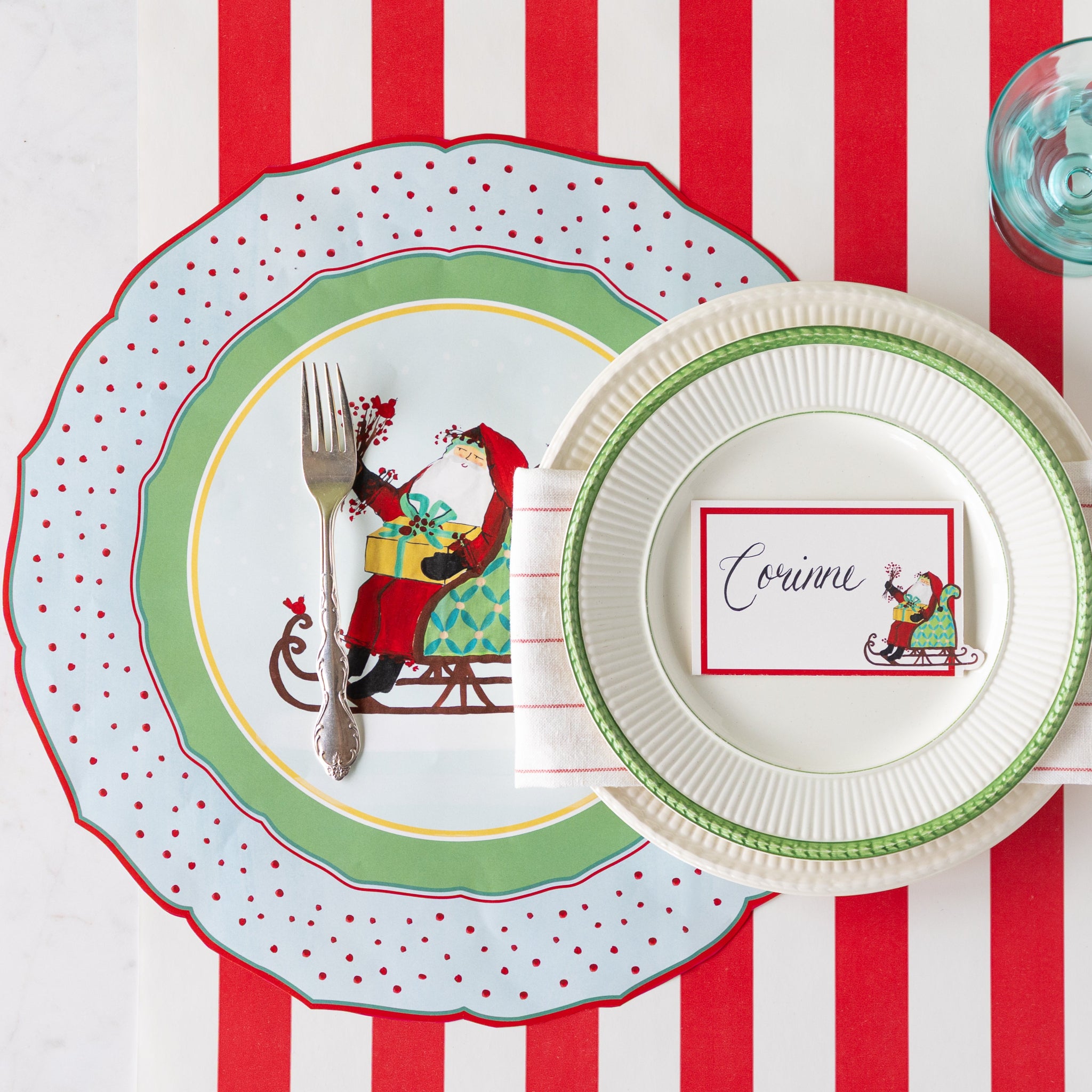 Christmas-themed place setting with the Die-cut Old St. Nick Placemat, vintage dinnerware with Old St. Nick Place Card atop, on the Red Classic Stripe Runner.