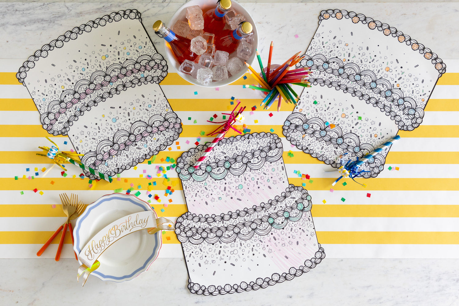 Die-cut Coloring Birthday Cake Placemats on a table with coloring pencils, confetti and an ice bucket of bottled drinks on the Marigold Classic Stripe Runner.