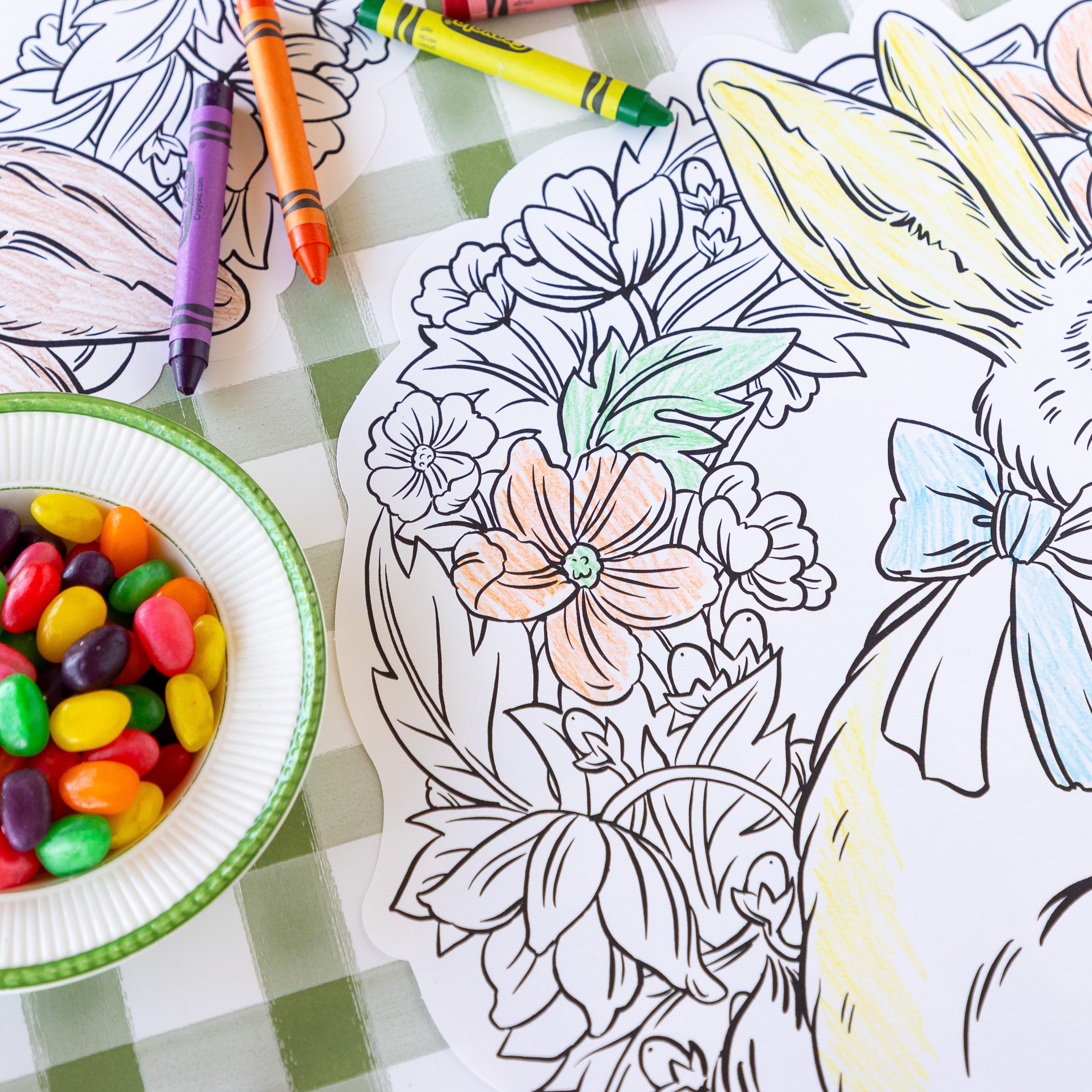Die-cut Coloring Bunny Wreath Placemats with crayons and jelly beans on the Moss Painted Check Runner.