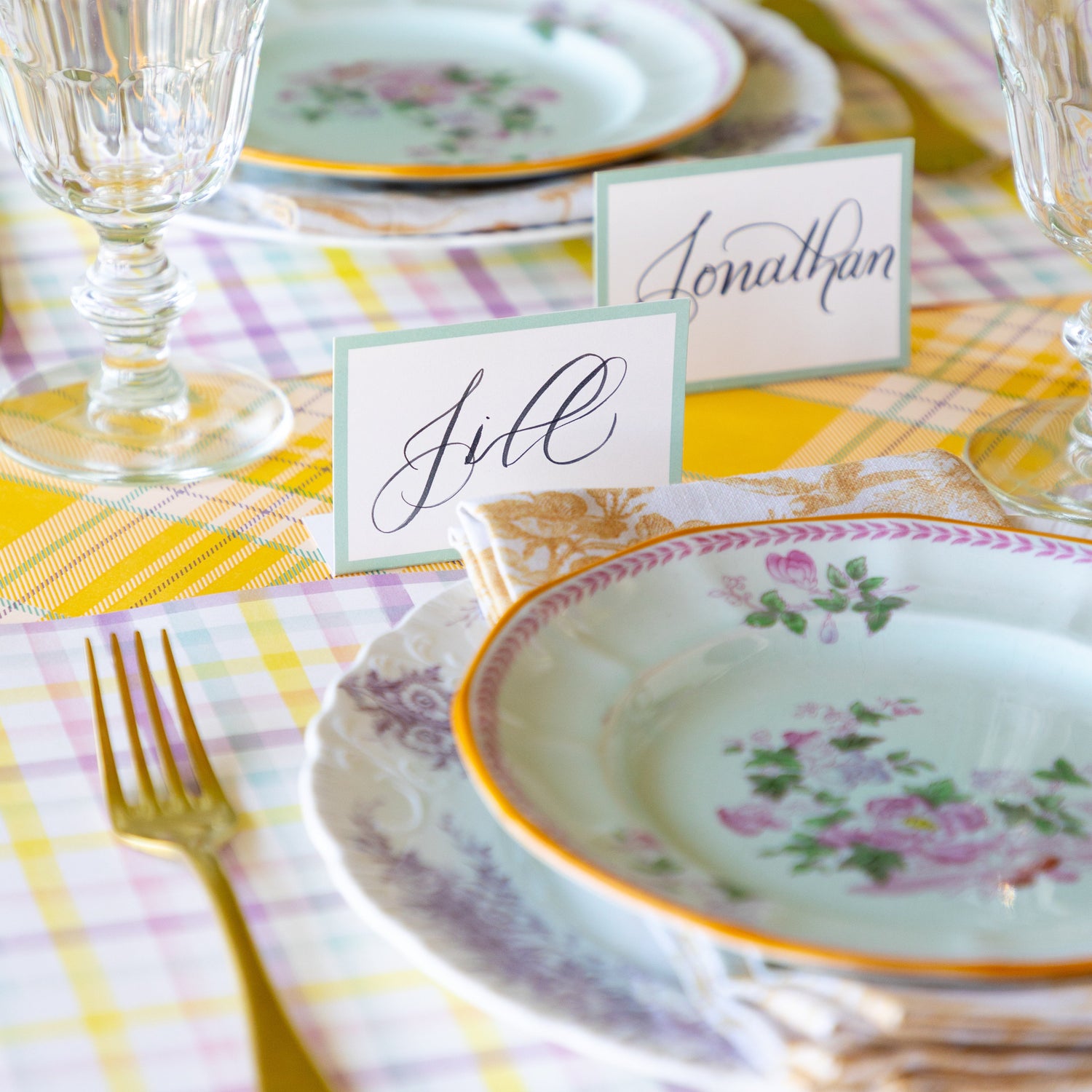 Table setting with floral plates, glasses, and Seafoam Frame Place Cards on the Yellow Plaid Runner.