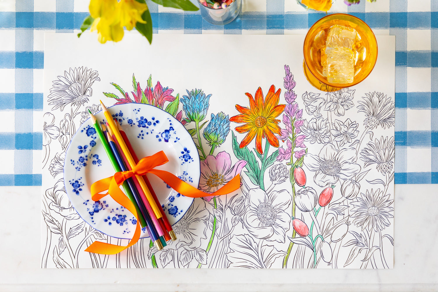 Coloring Wildflower Meadow Placemat with colored pencils and a plate on the Blue Painted Check Runner.