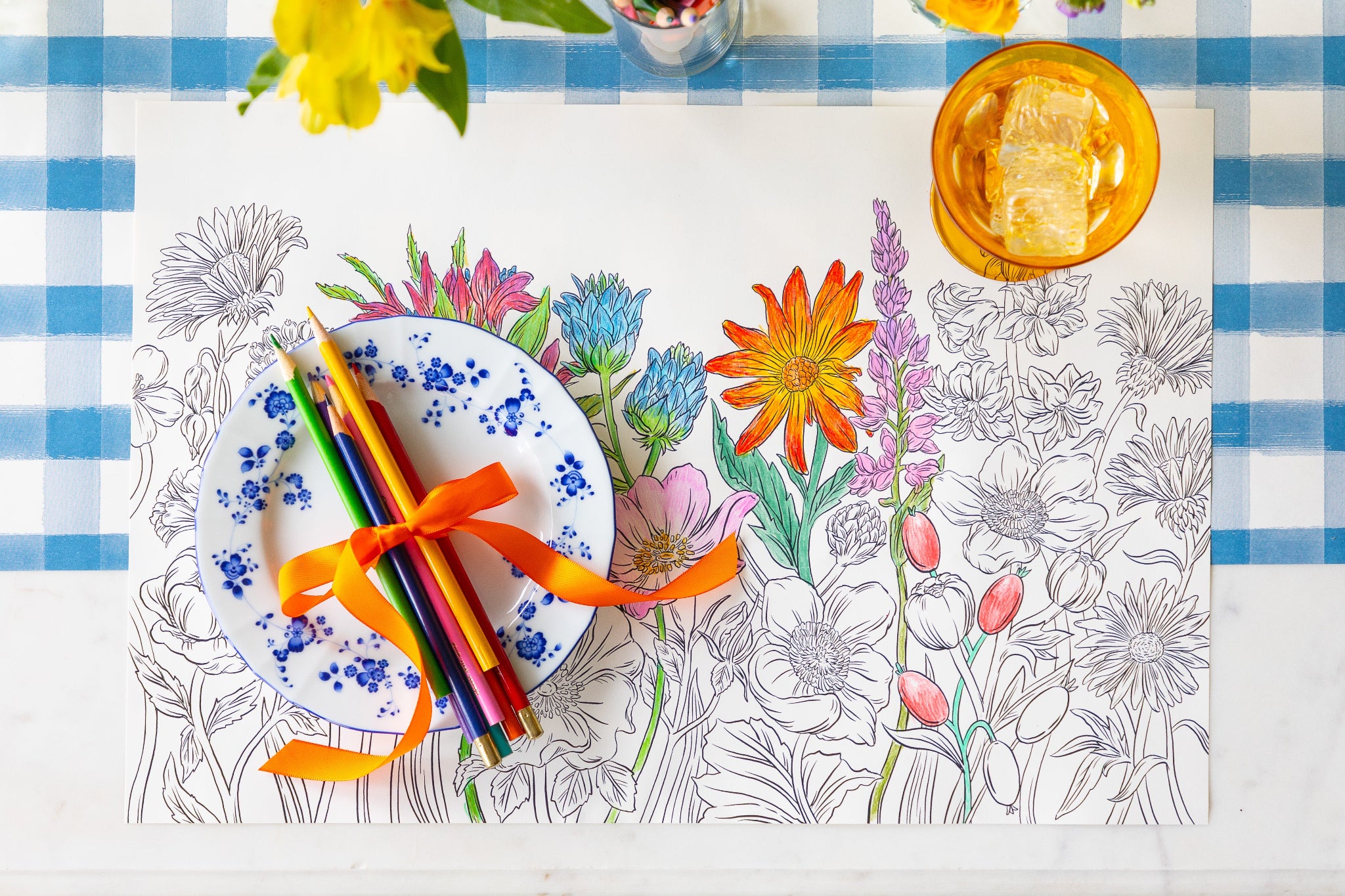 Coloring Wildflower Meadow Placemat with colored pencils and a plate on the Blue Painted Check Runner.