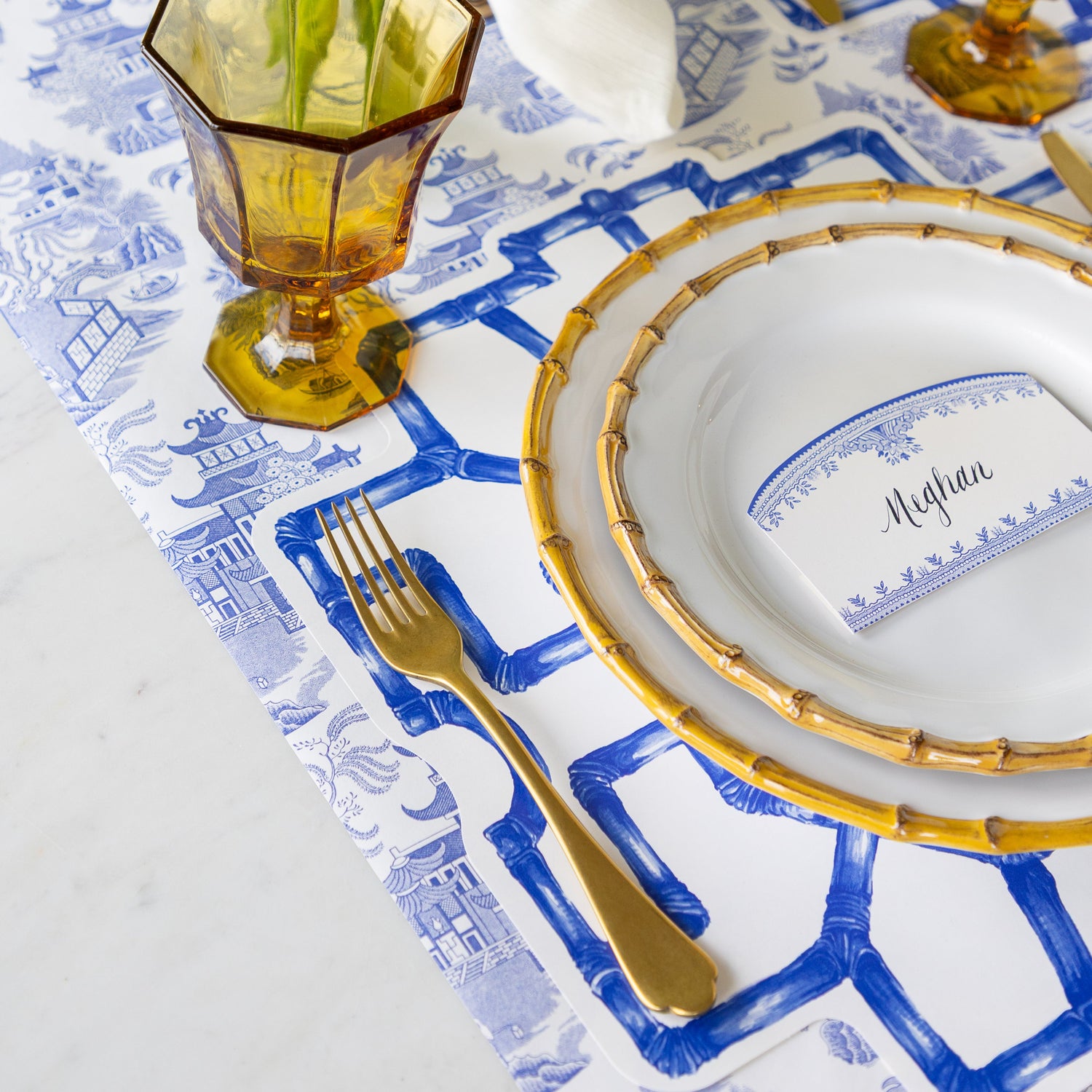 Elegant table setting with Die-cut Blue Bamboo Placemat, bamboo-rimmed plates, and amber glass on the Blue Regal Peacock Runner.