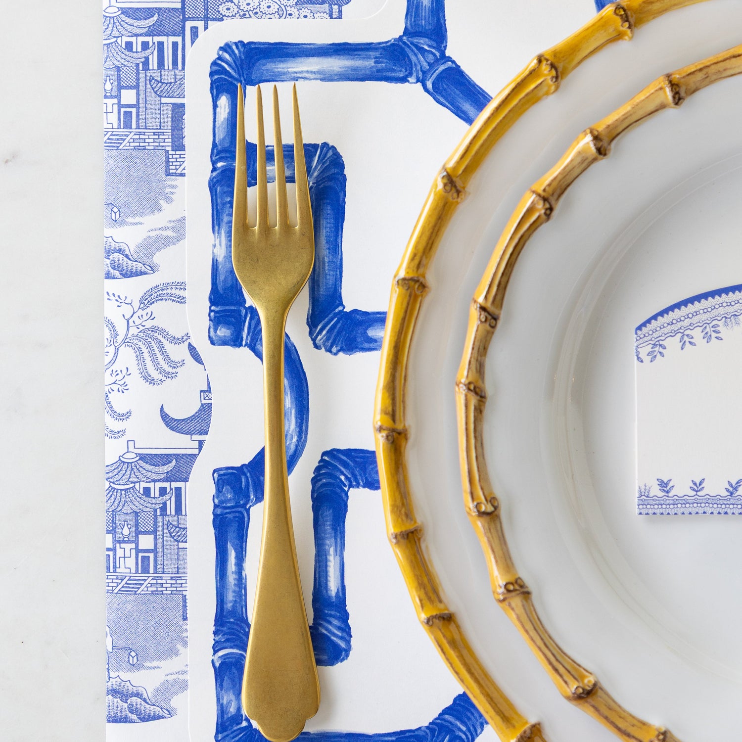 Gold fork and plates on the Die-cut Blue Bamboo Placemat.