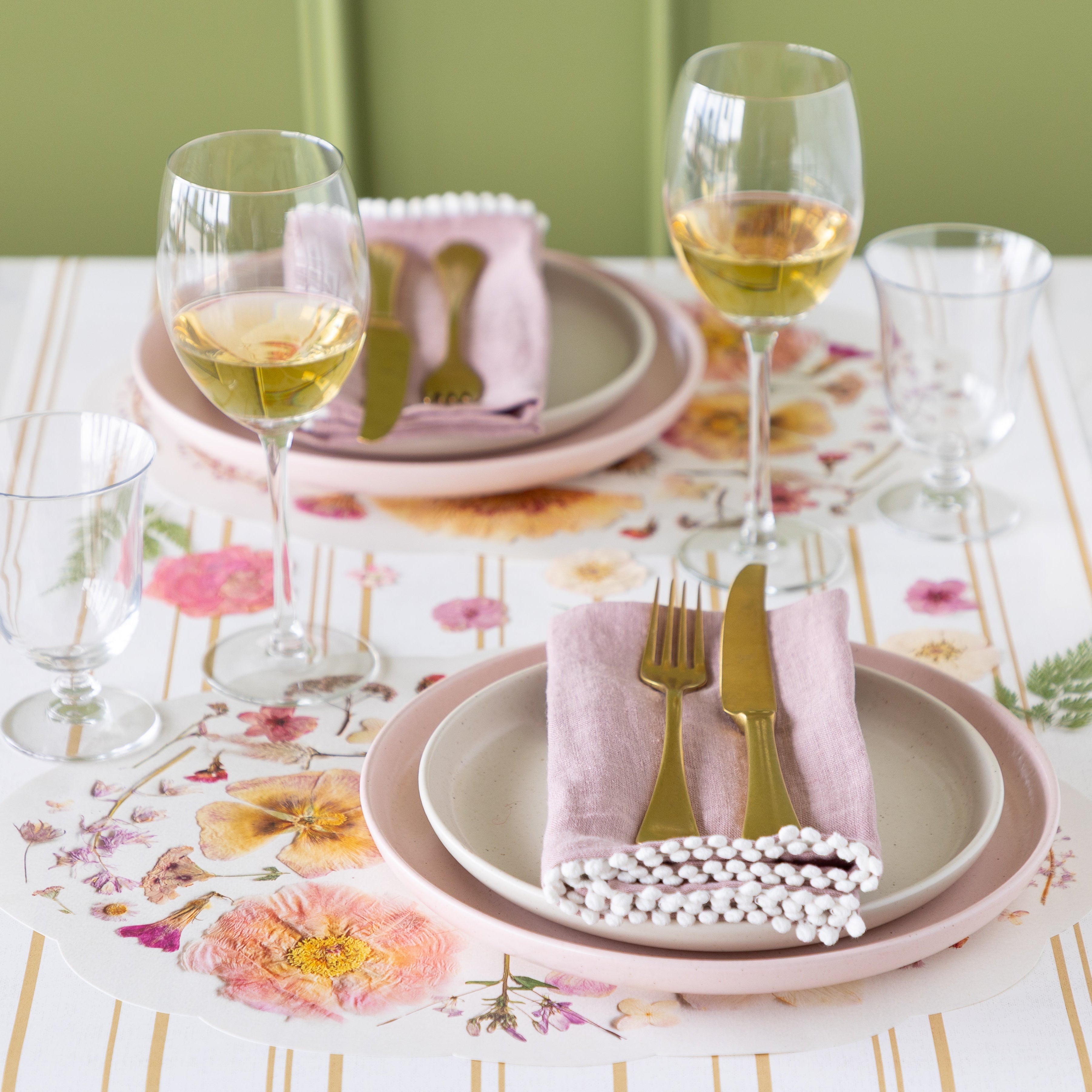 Dining table setting with Die-cut Blush Petals Placemats, glasses, and cutlery on the Antique Gold stripe Runner.