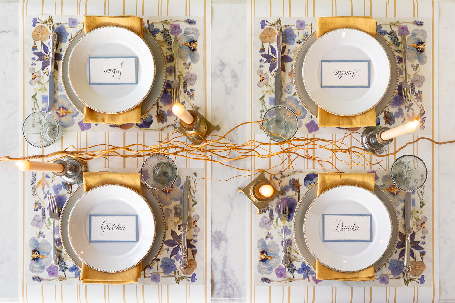 Elegant table setting with Periwinkle Pressed Petals Placemat, decorative plates, Cornflower Blue Place Card and decorative elements on the Antique Gold Stripe Runner.