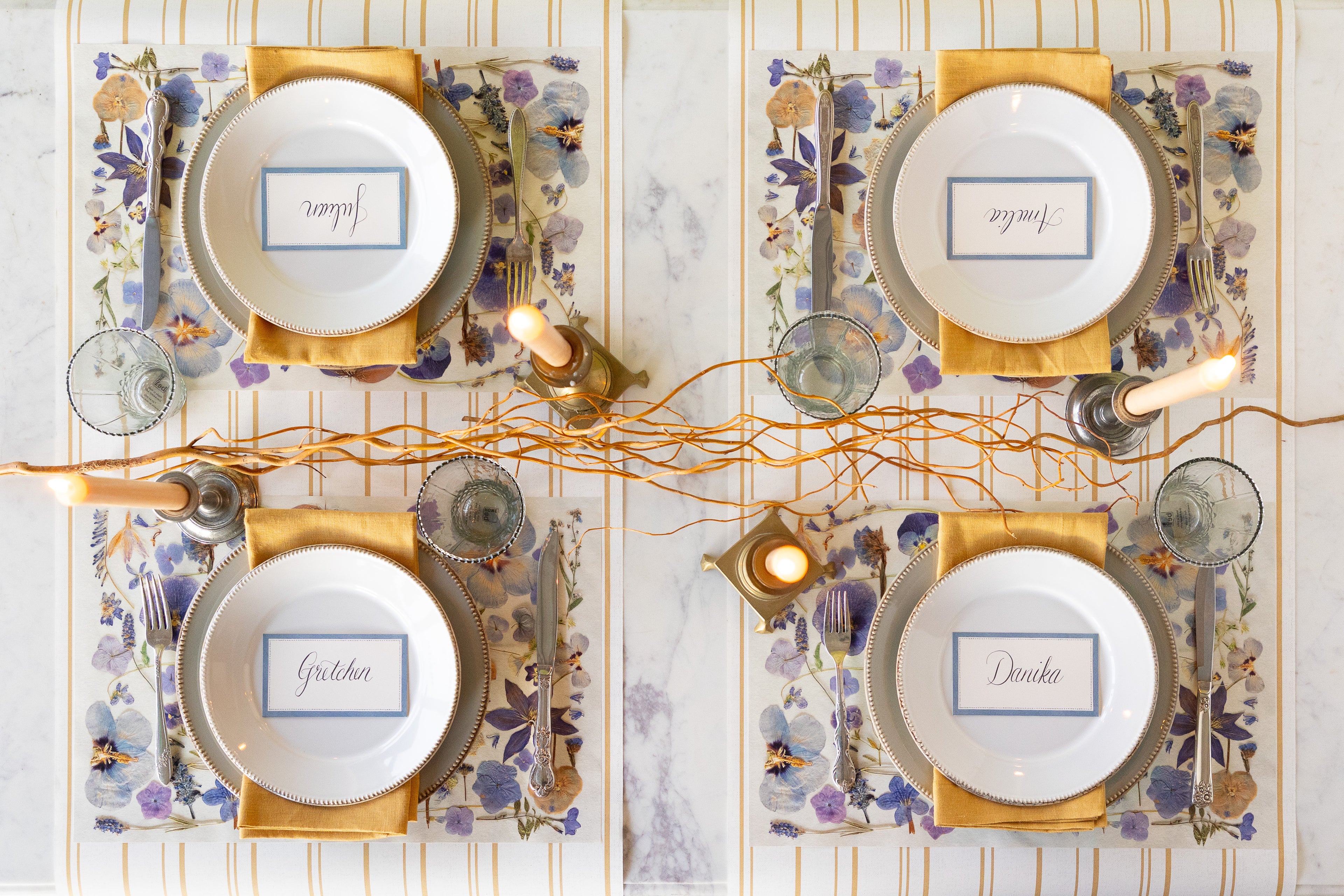 Elegant table setting with Periwinkle Pressed Petals Placemat, decorative plates, Cornflower Blue Place Card and decorative elements on the Antique Gold Stripe Runner.