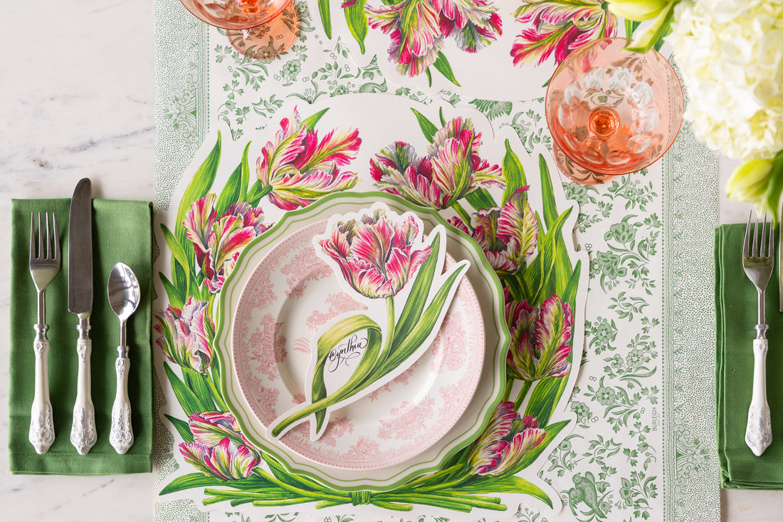 Table set with the Die-cut Parrot Tulip Placemat, green rimmed and pink floral plate, Parrot Tulip Table Accent, flowers, a green napkin and vintage flatware on the Green Regal Peacock Runner.