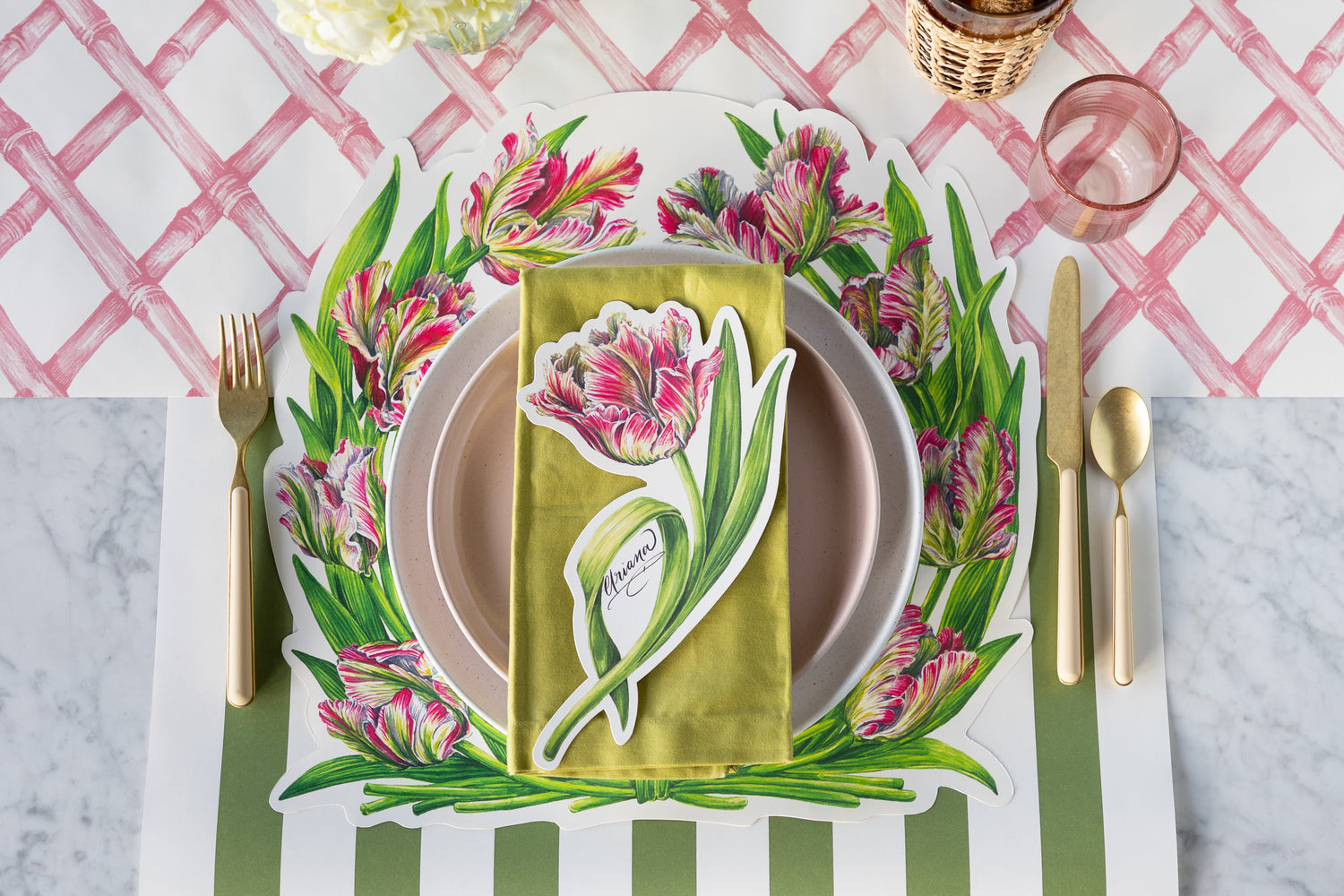 A place setting with the Die-cut Parrot Tulip Placemat on the Pink Lattice and Moss Green Classic Stripe Runners.